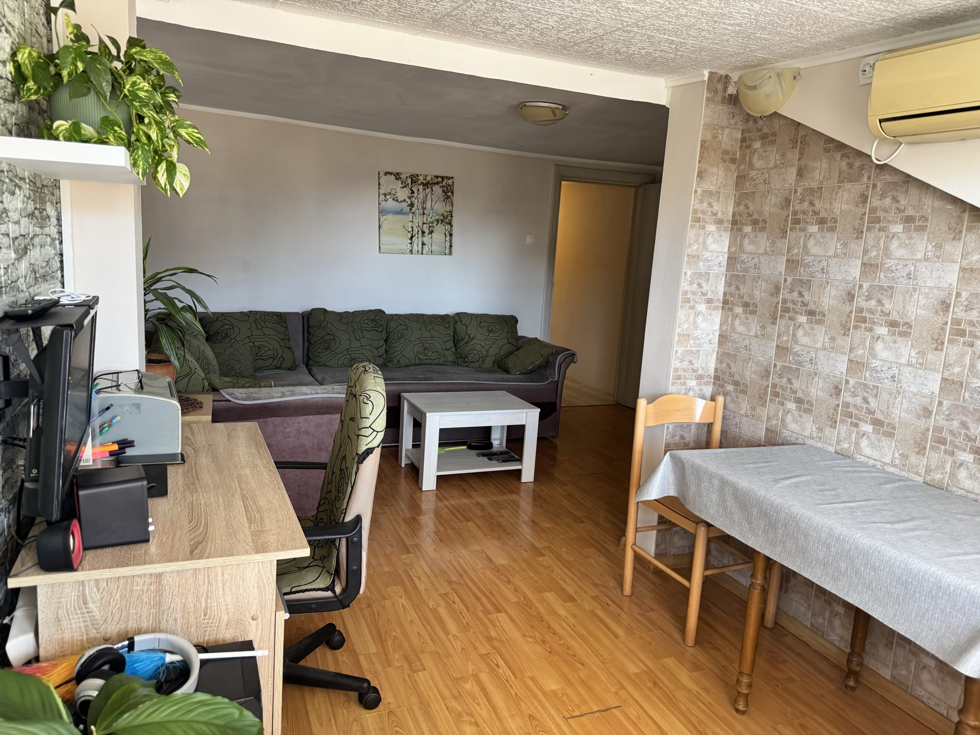 Living room in an apartment in Bečići, Montenegro: a soft sofa, dining area, workspace, and parquet flooring.