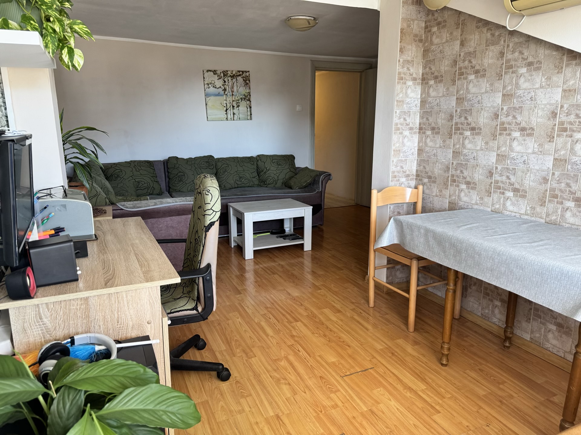 Living room in an apartment in Bečići, Montenegro: sofa, dining area, desk, and walls finished with decorative tile.