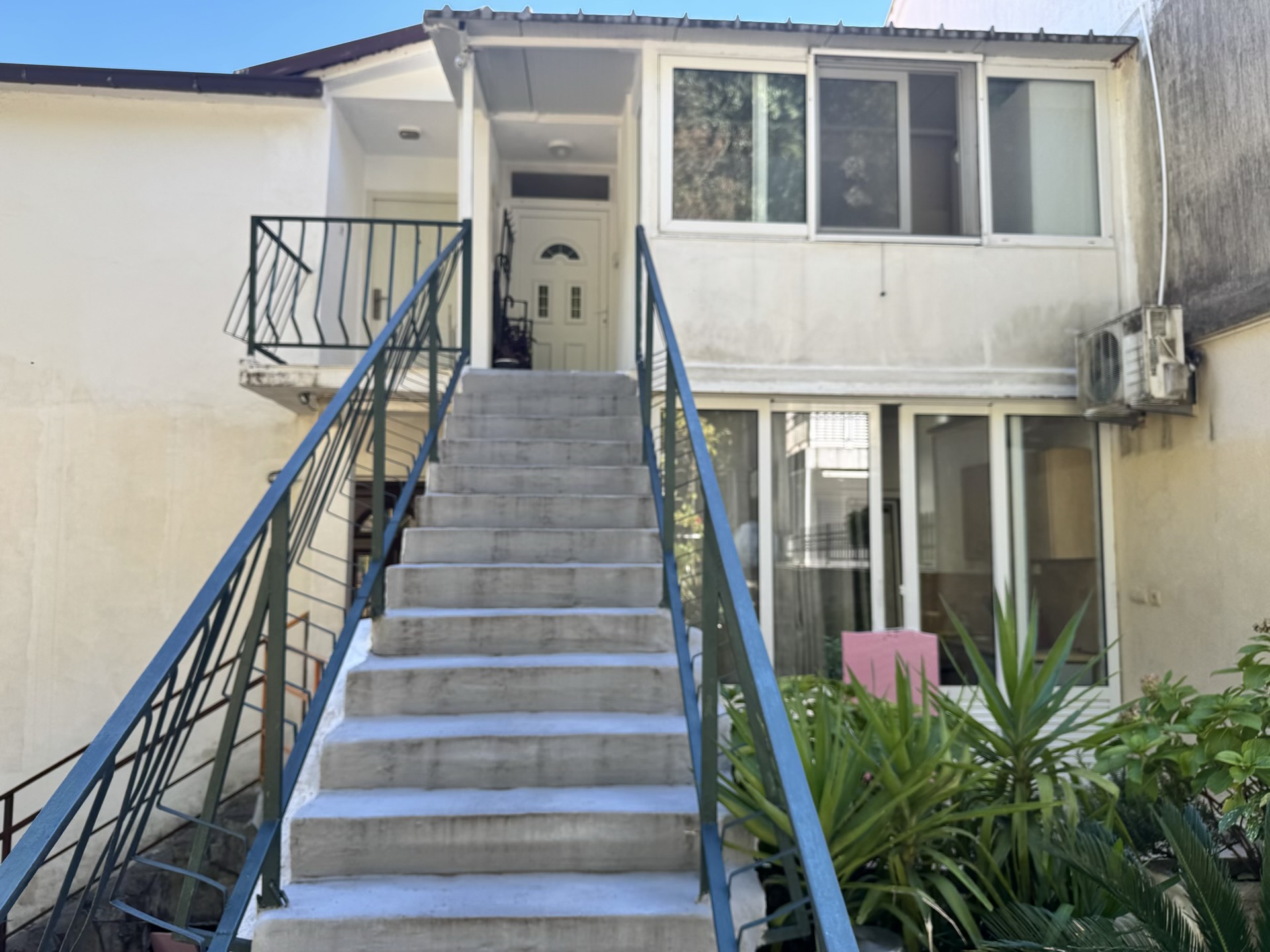Entrance to the apartment in Bečići, Montenegro: concrete stairs with metal railings and the building facade with panoramic windows.