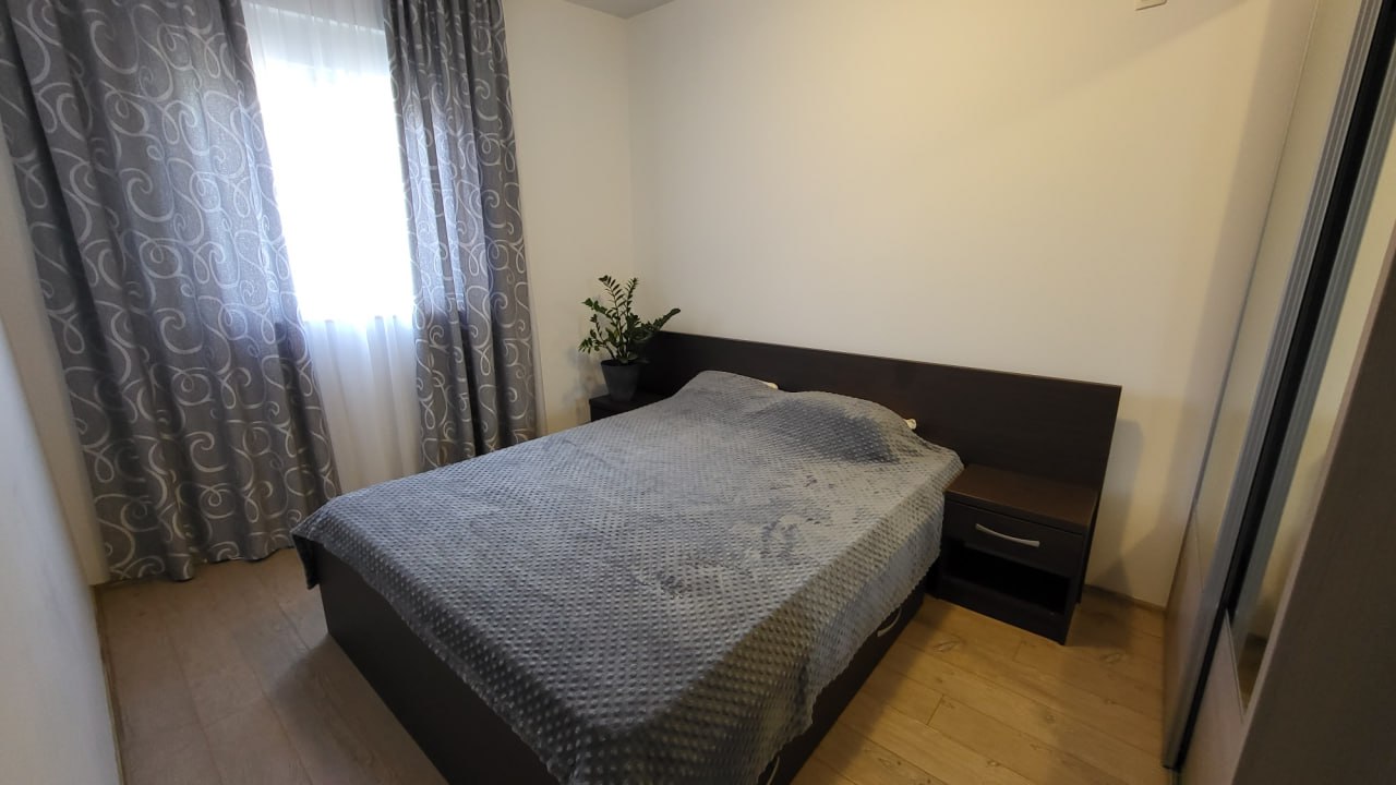Cozy bedroom in an apartment in Bečići, Montenegro: a double bed, dark furniture, light walls, and patterned curtains.