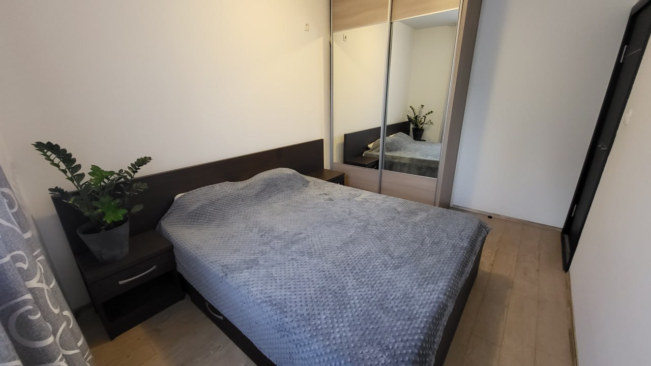 Bedroom in an apartment in Bečići, Montenegro: a double bed, a mirrored sliding wardrobe, and a bedside table.