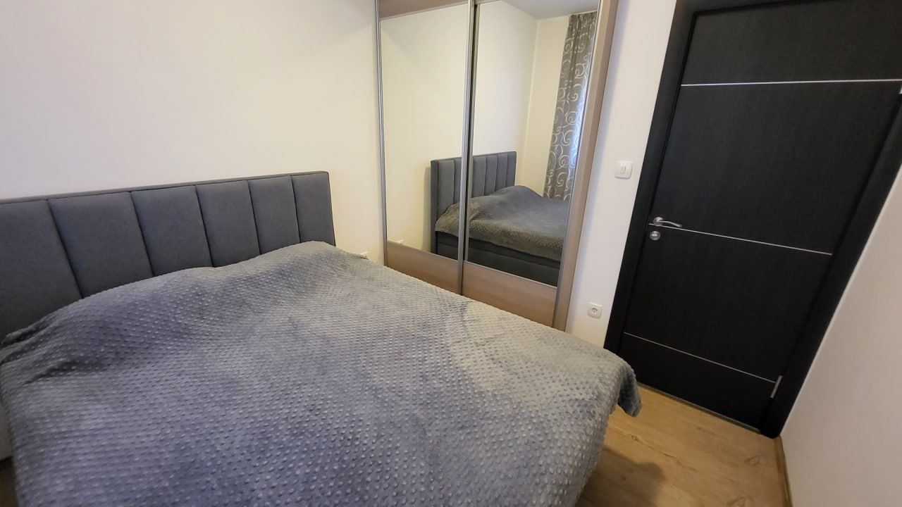 Bedroom in an apartment in Bečići, Montenegro: a double bed with a padded headboard and a mirrored sliding wardrobe.