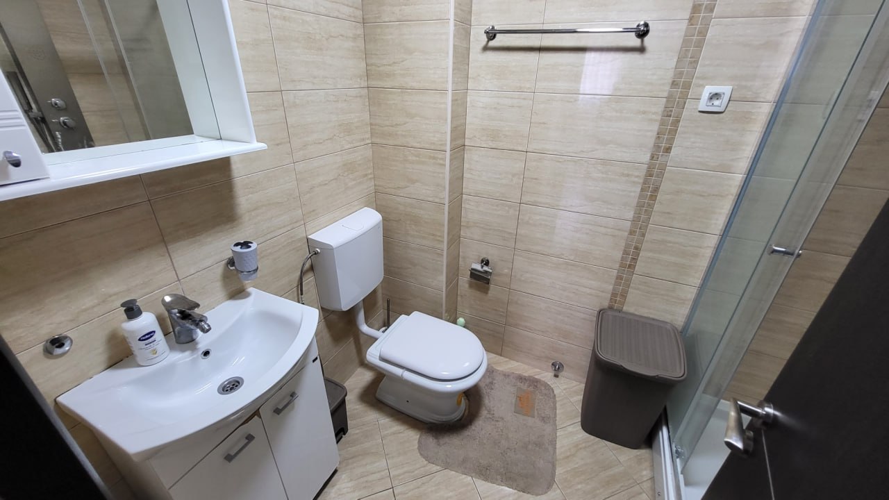 Modern bathroom in an apartment in Bečići, Montenegro: white fixtures, shower cabin, and beige tiles.