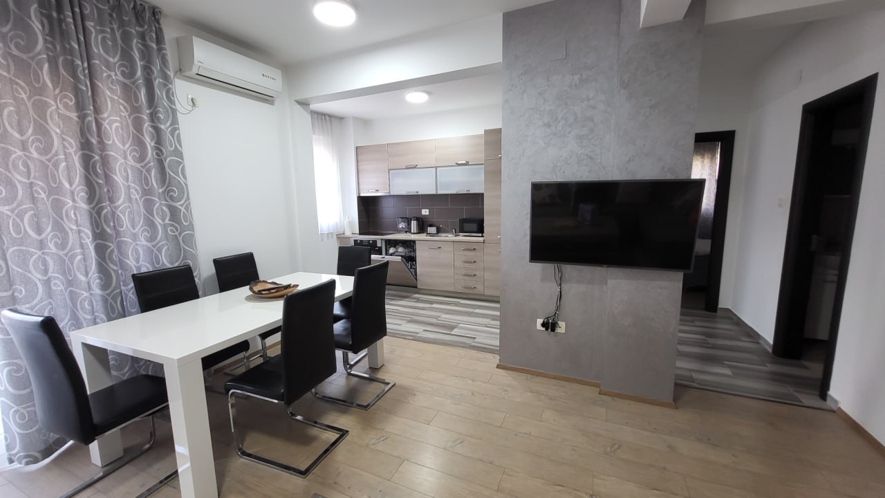 Living room with dining area and modern kitchen in an apartment in Bečići, Montenegro: bright interior, TV and furniture.