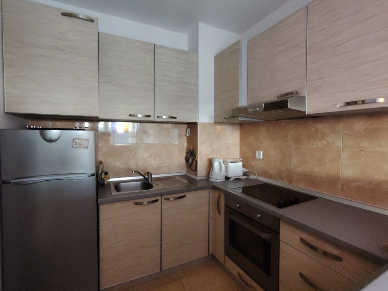 Modern kitchen in an apartment, Sceoce, Montenegro: light-colored cabinets, built-in appliances, refrigerator and stove.