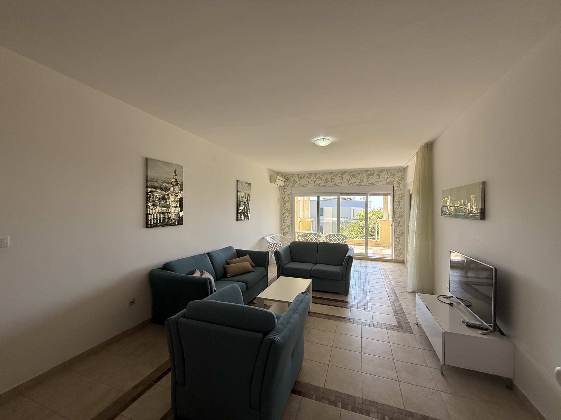 Bright living room with blue sofas and access to the terrace in an apartment in Budva, Montenegro. Tiled floor, modern style.