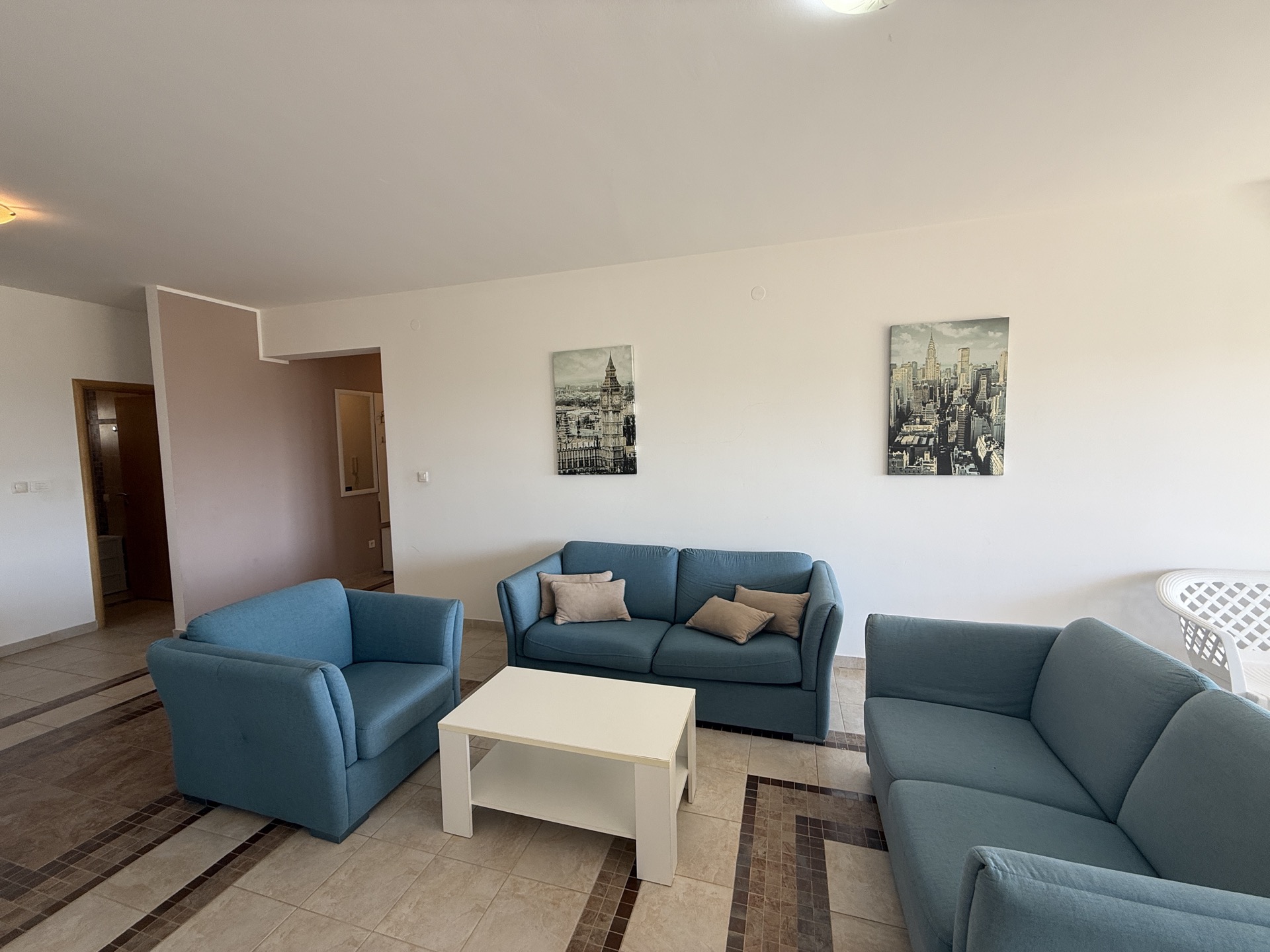Bright living room with blue upholstered furniture in an apartment for sale in Budva, Montenegro: sofas, armchair, and coffee table.