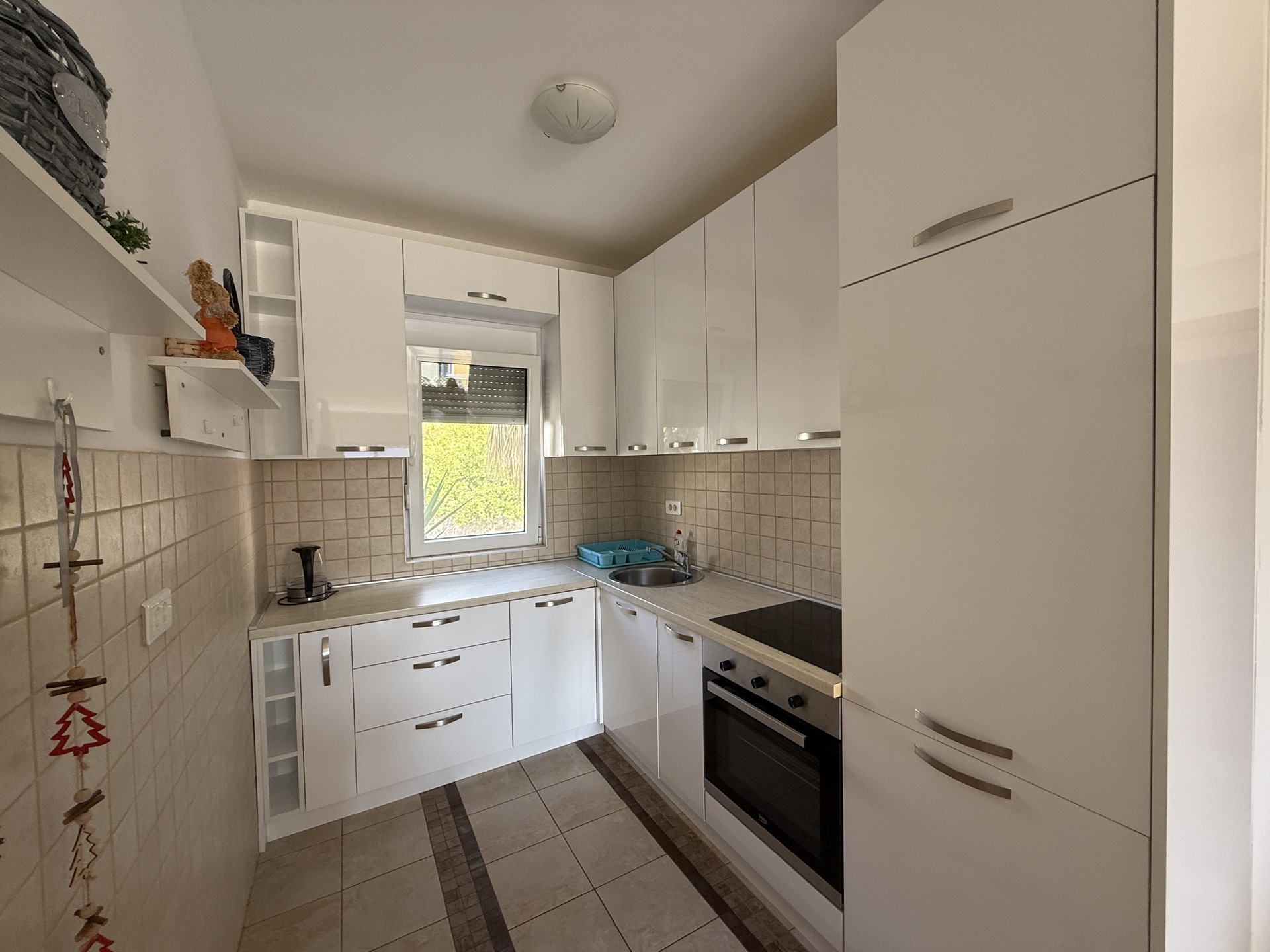 Modern white kitchen with glossy fronts and built-in appliances in an apartment, Budva, Montenegro.
