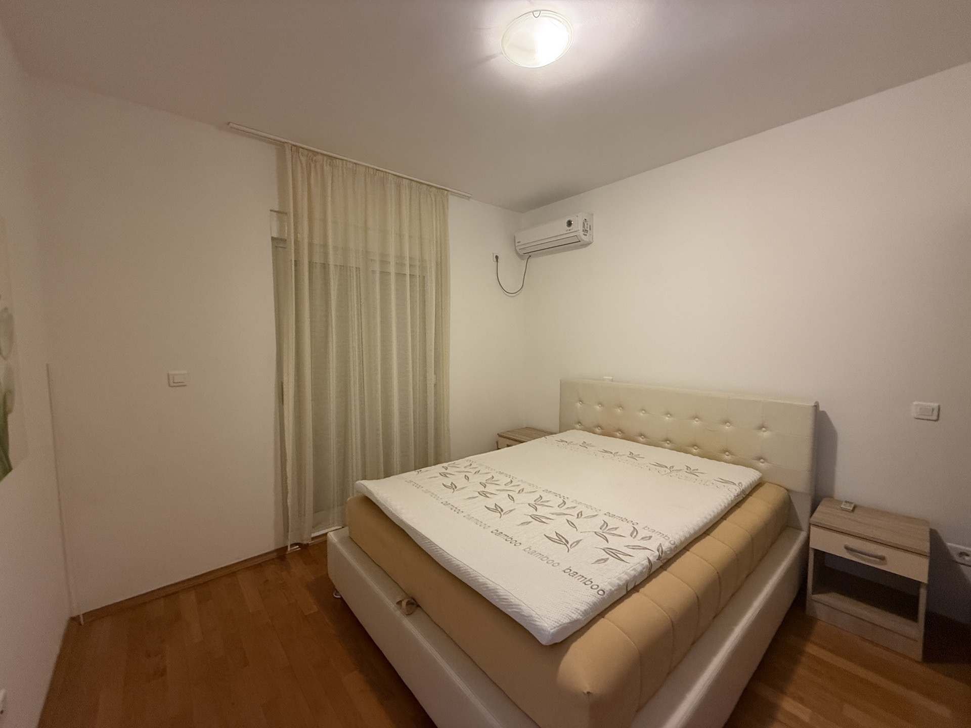 Bright bedroom with a double bed and air conditioning in an apartment in Budva, Montenegro, with access to the balcony.
