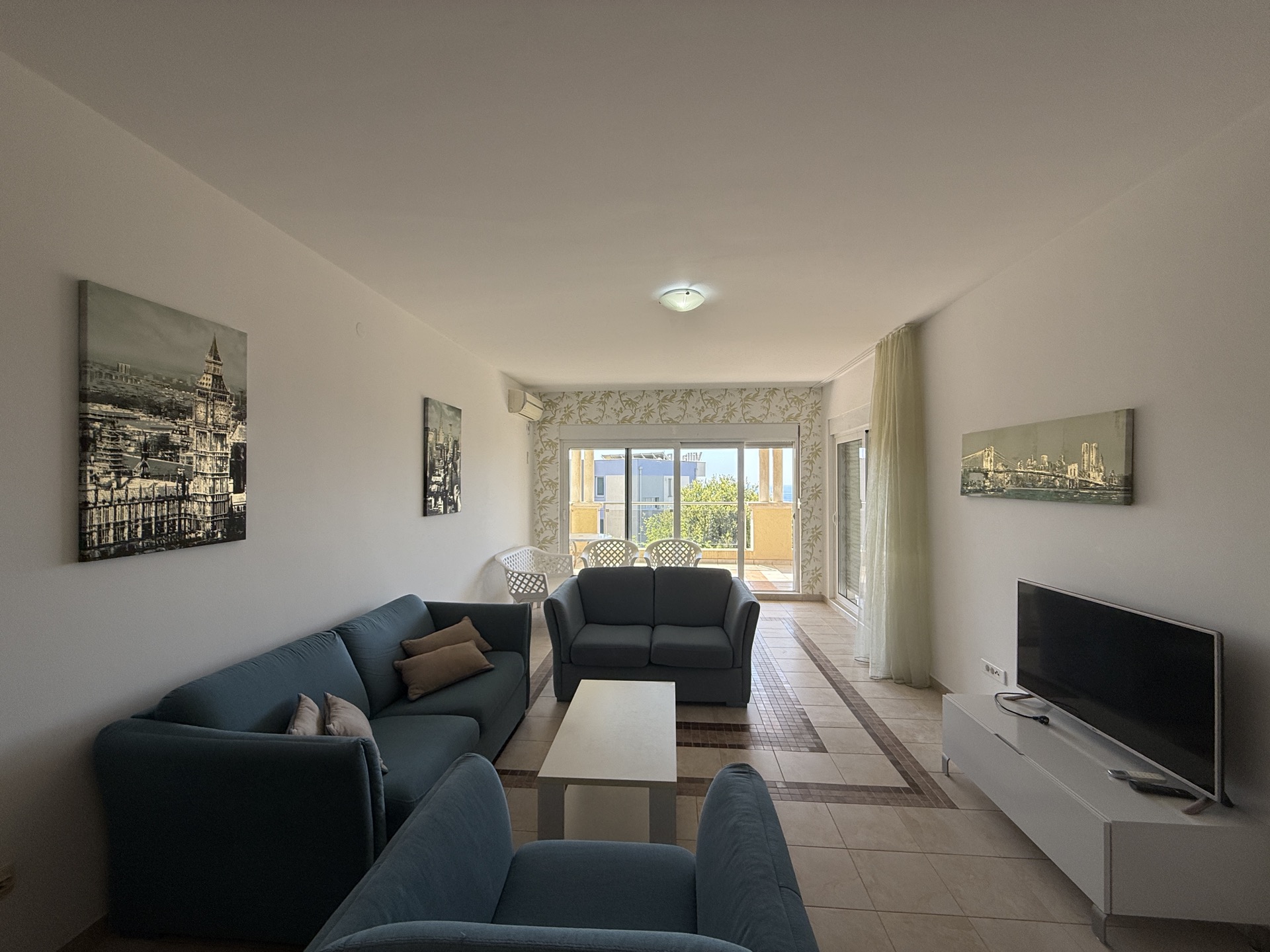 Bright living room with blue sofas and access to the terrace in an apartment in Budva, Montenegro.