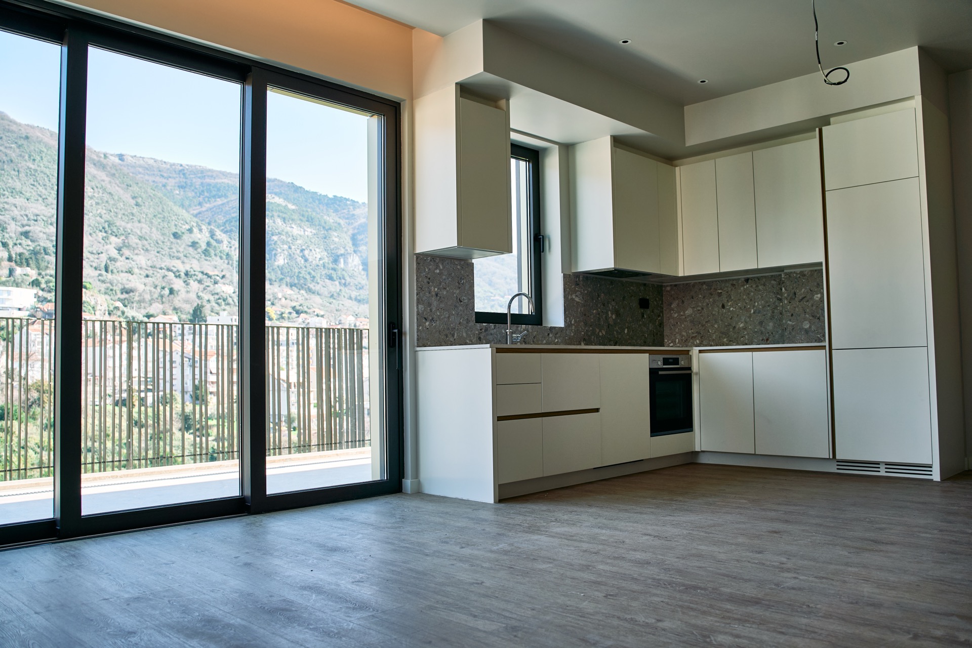 Modern kitchen in an apartment in Porto Montenegro, Tivat, Montenegro: light-colored cabinetry, mountain view, and panoramic windows.