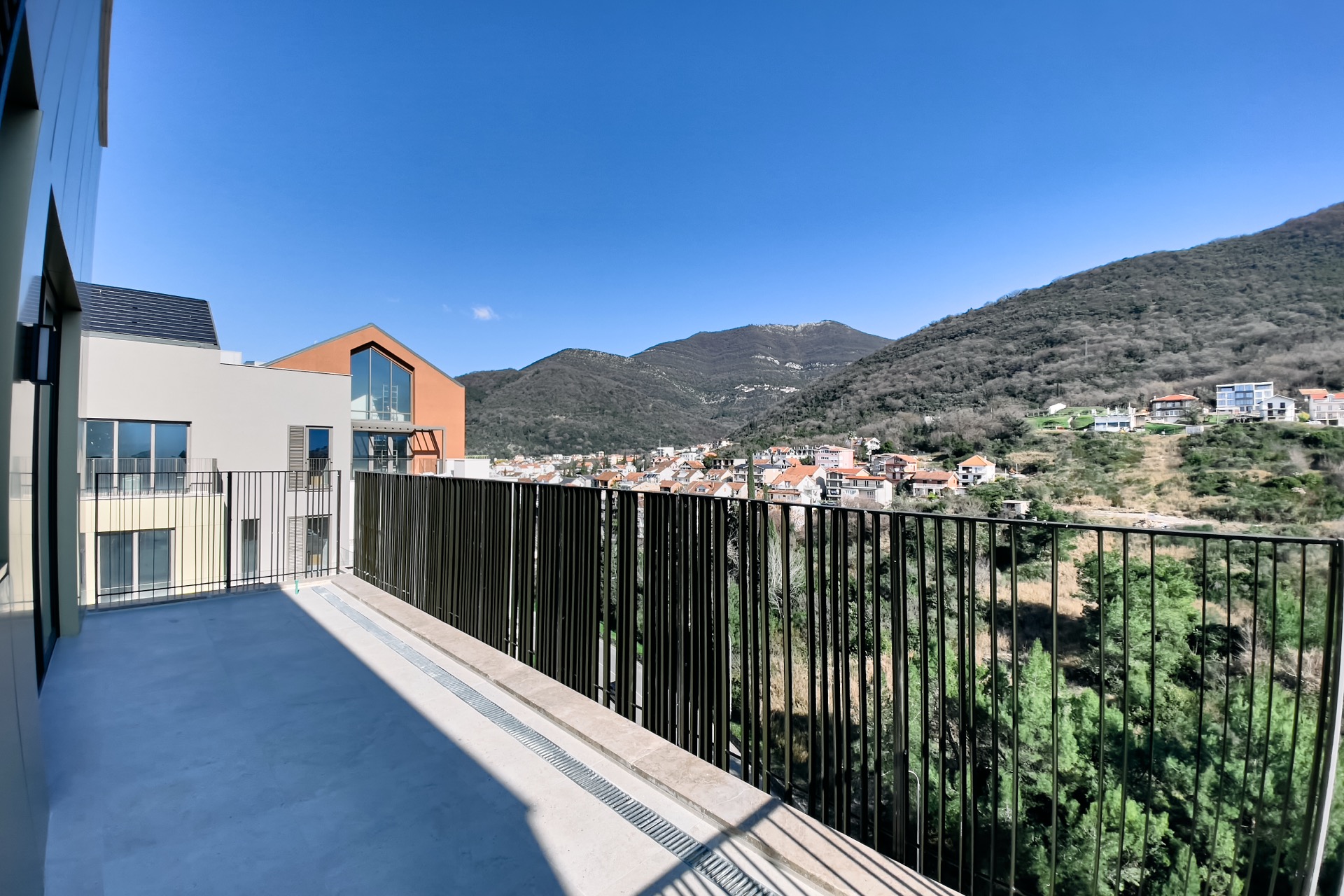 Spacious balcony of a modern apartment in Porto Montenegro, Tivat, Montenegro, with panoramic views of the mountains and the city.