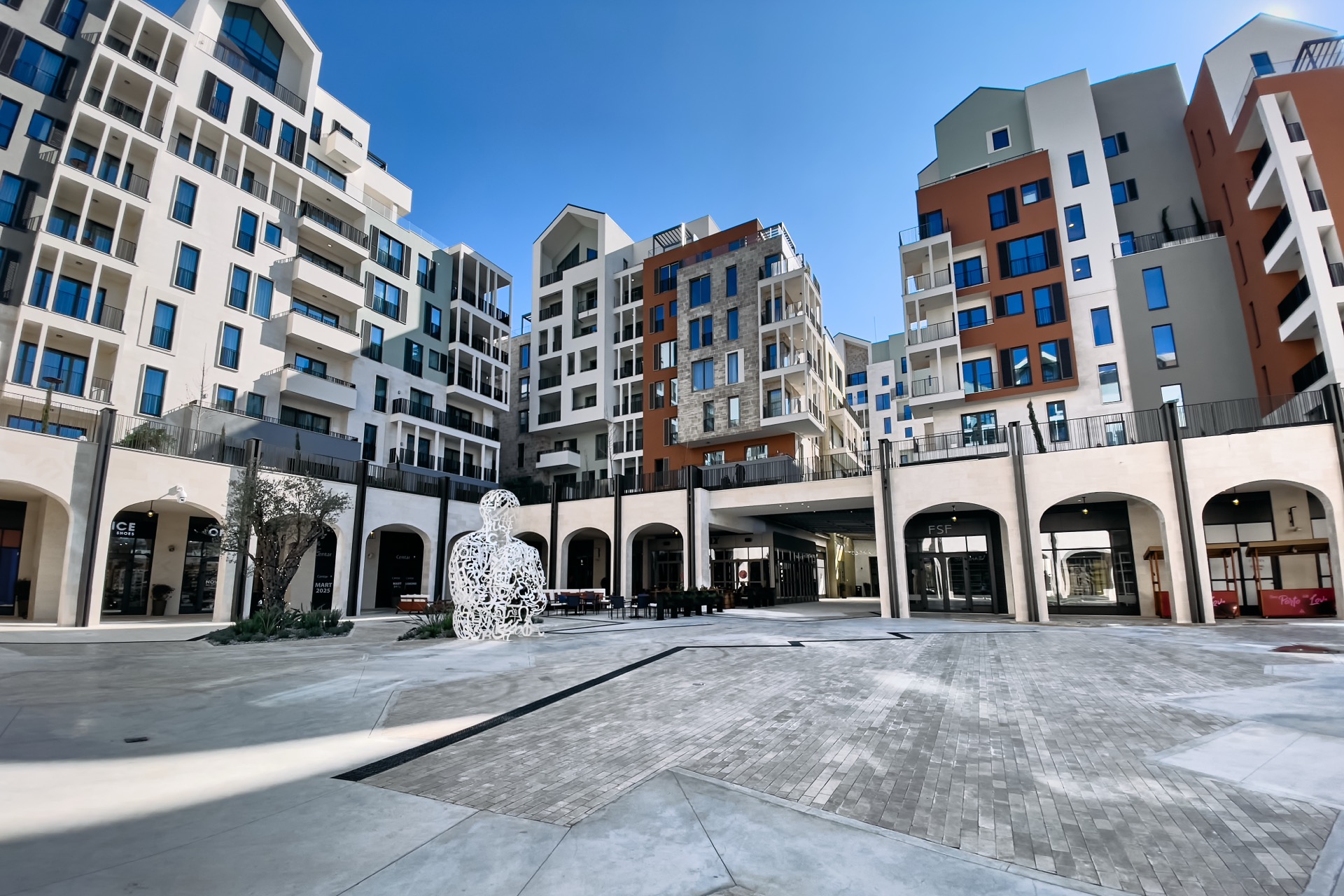 Modern residential complex in Porto Montenegro, Tivat: building architecture, an art installation in the square, and shopping galleries.