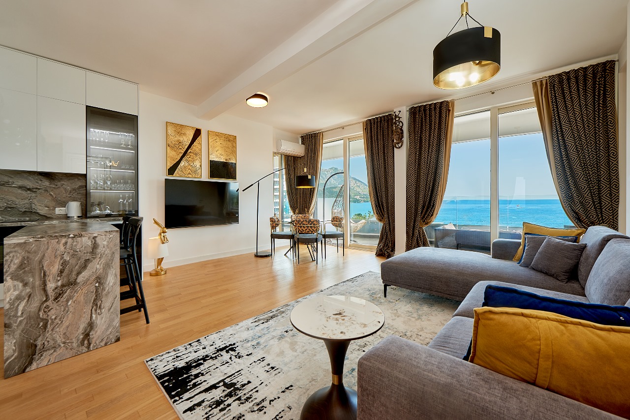 Modern living room with kitchen in an apartment in Bečići, Montenegro: panoramic sea view, marble bar counter, and terrace.