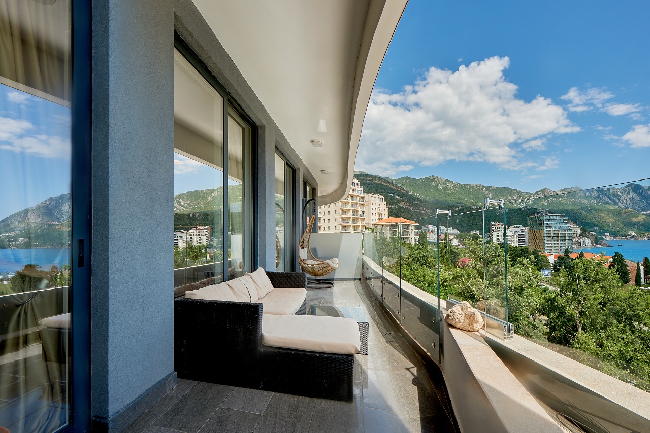 Spacious balcony with wicker furniture and sea and mountain views in an apartment, Bečići, Montenegro.