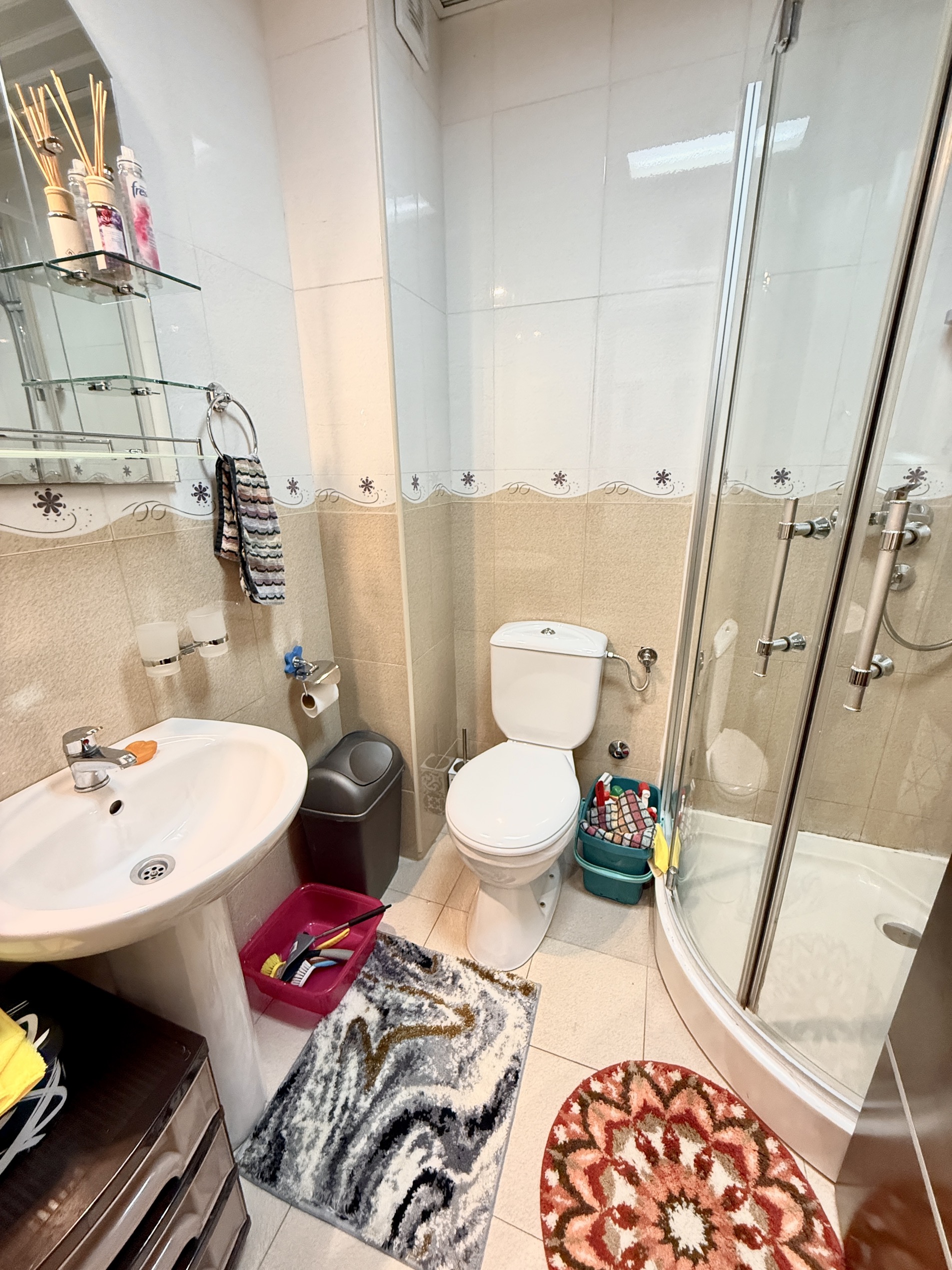 Bathroom in an apartment in Budva, Montenegro: shower cabin, sink, toilet, and light tile finish.