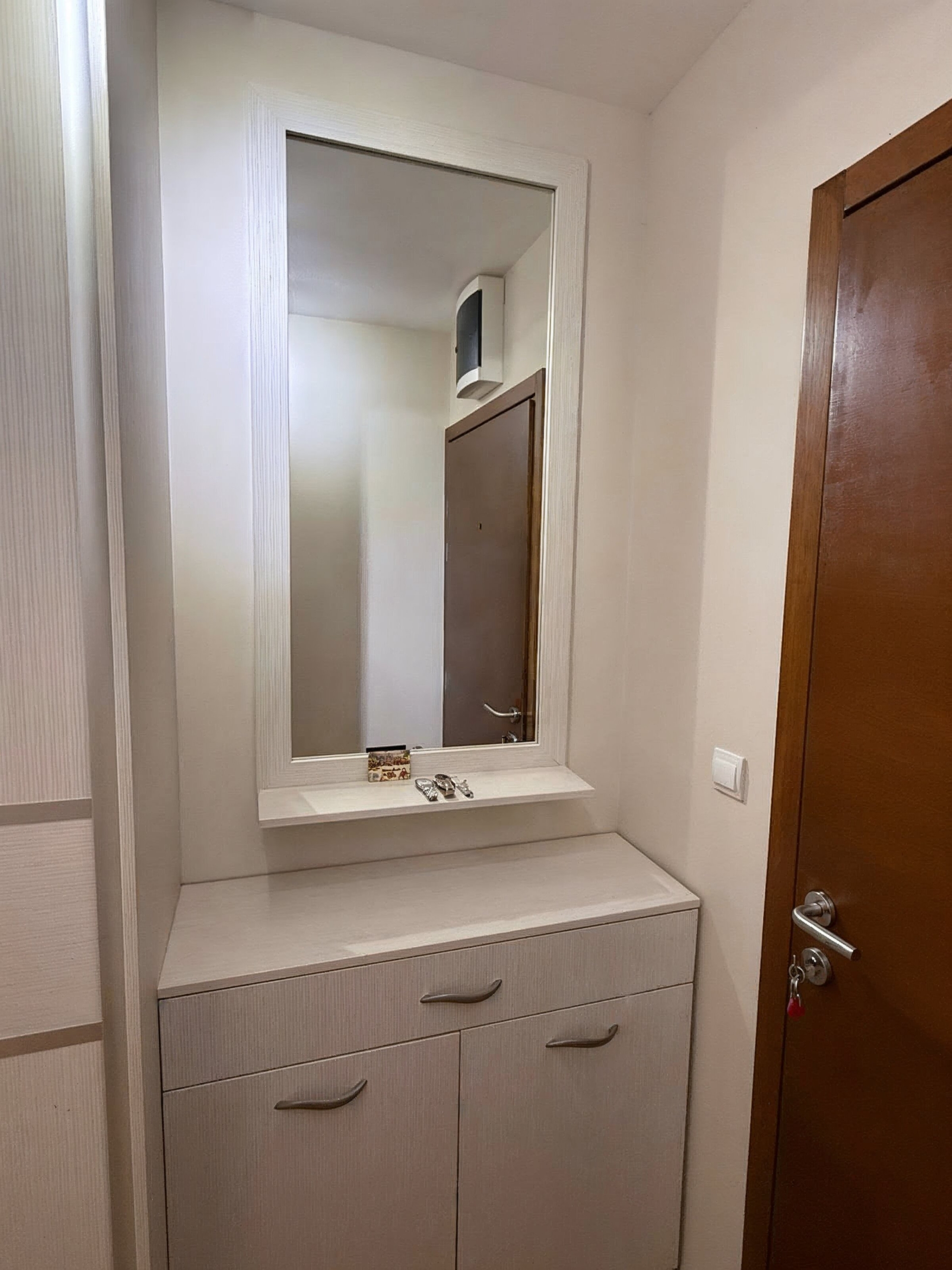Hallway with a white cabinet and mirror in a modern apartment in Bečići, Montenegro. Interior of property No. 2510.