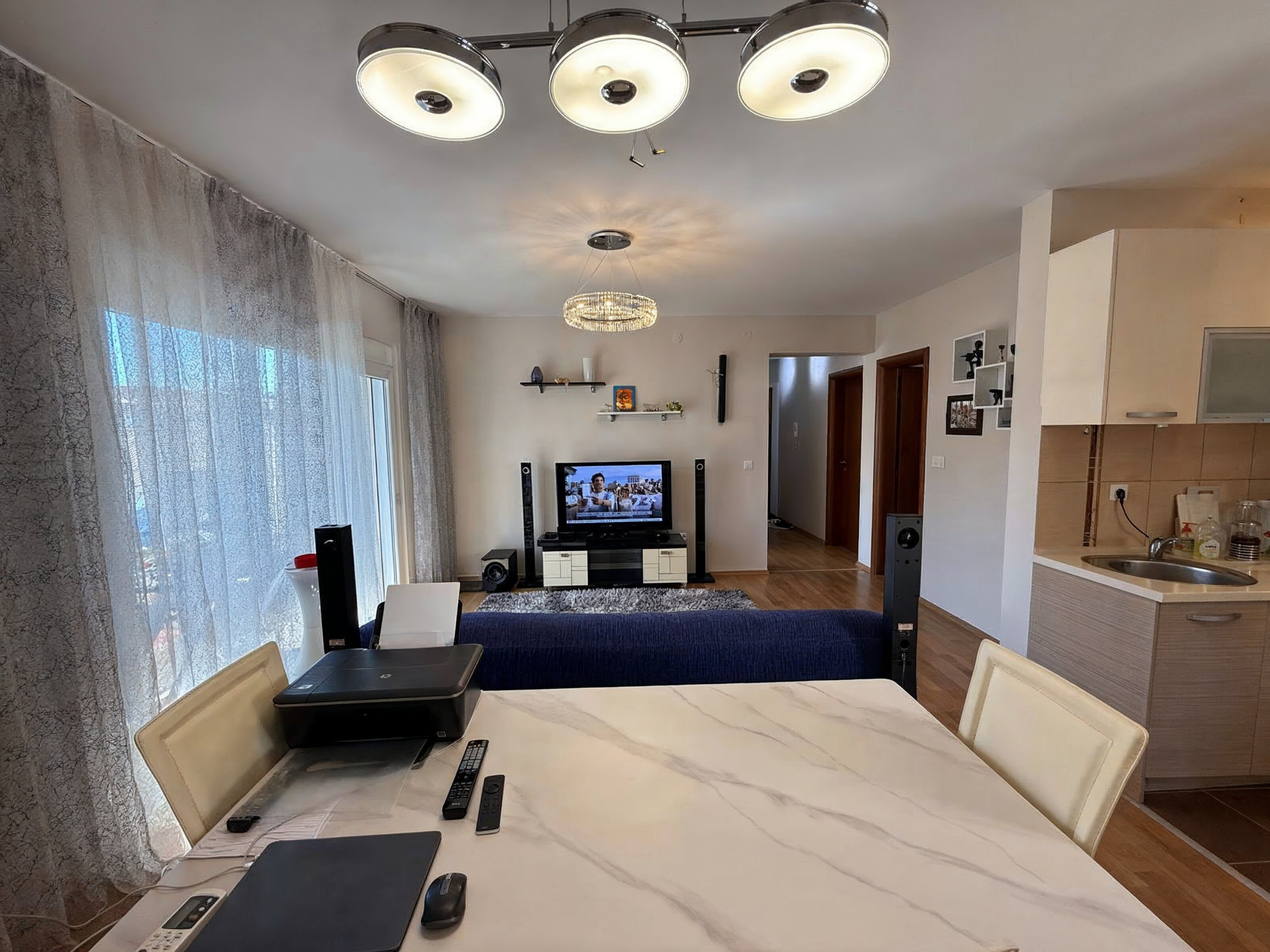 Living room with dining area and kitchen in an apartment, Bečići, Montenegro: bright interior, marble table, TV area.