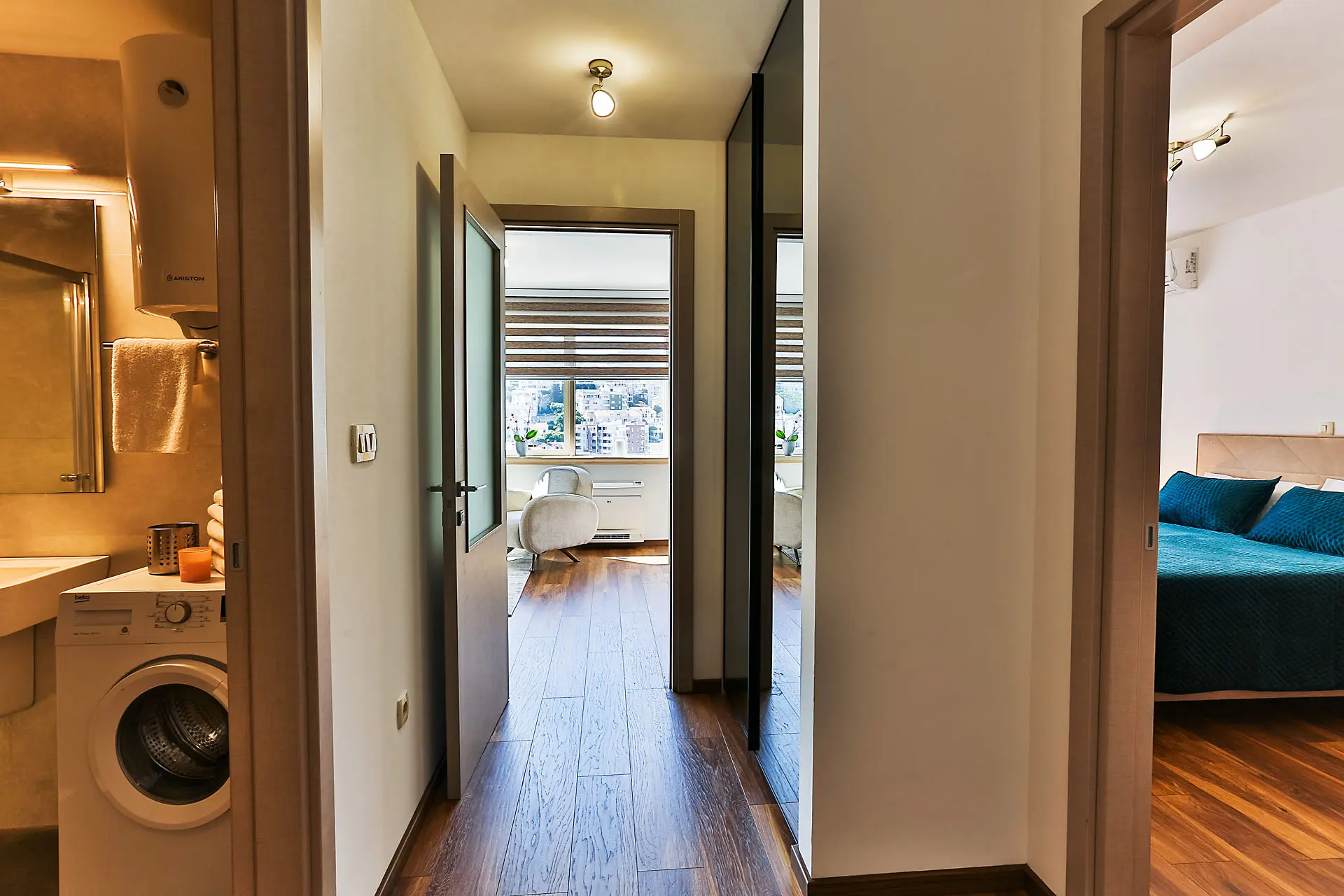 Hallway in an apartment in Budva, Montenegro: view of the bedroom, bathroom with a washing machine, and living room with a window.