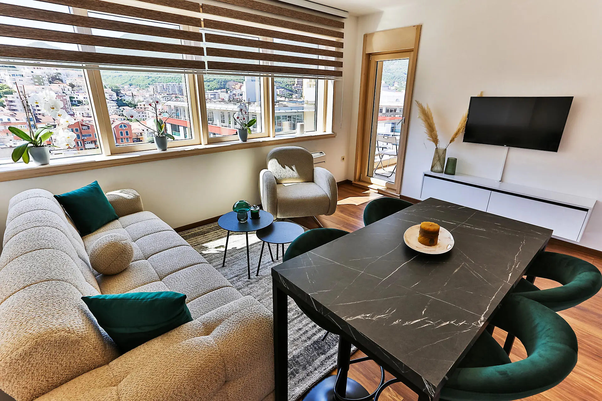 Modern living room with panoramic windows in an apartment in Budva, Montenegro: dining area and soft seating.