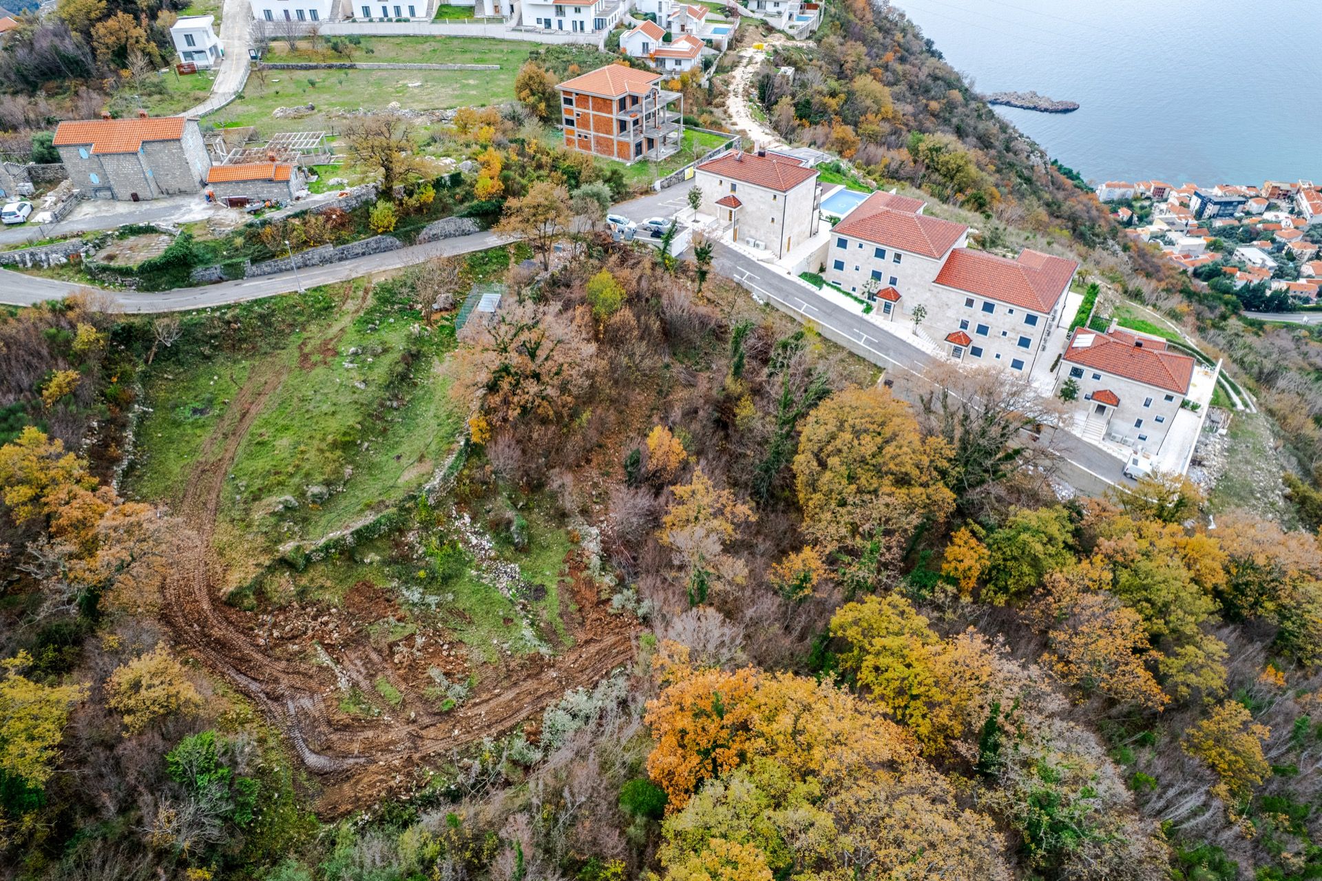 Aerial view of a residential complex in Blizikuće, Montenegro: modern houses with tiled roofs and a sea view.