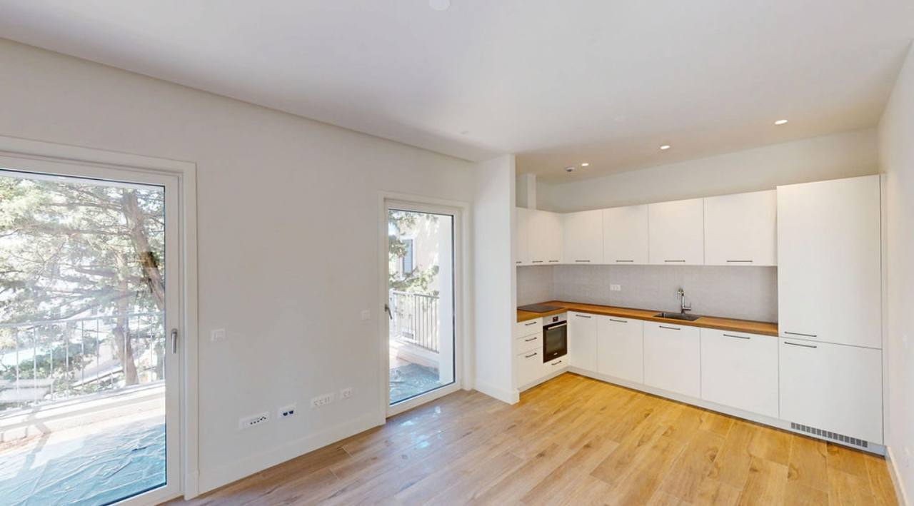 Modern white kitchen in an apartment in Lustica Bay, Montenegro: bright interior, wooden floor, and access to the terrace.