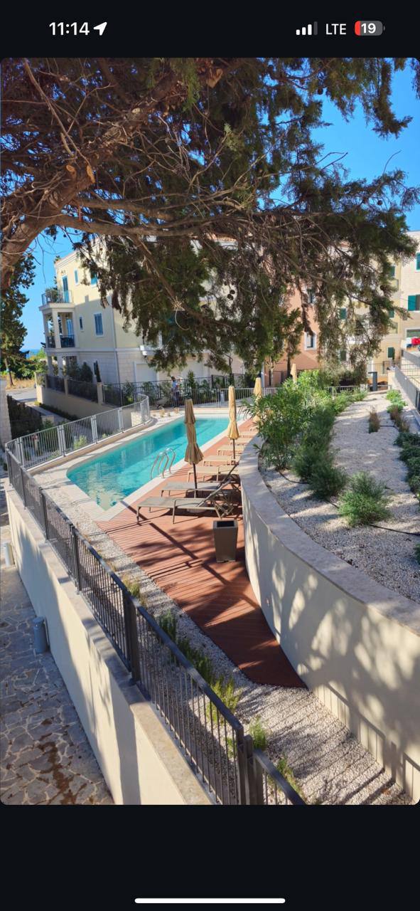 Outdoor swimming pool with sun loungers and a terrace in the Lustica Bay residential complex, Montenegro. View of the landscaped grounds.