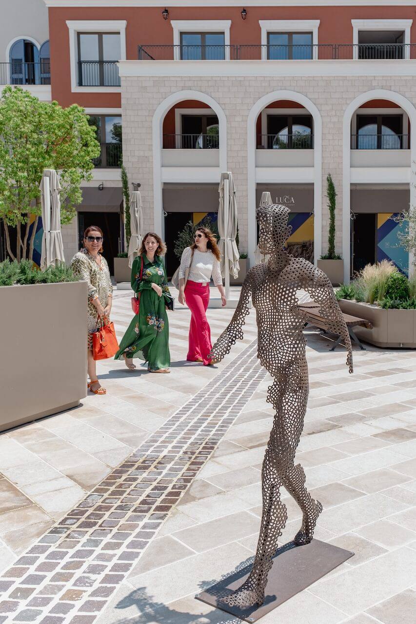 A modern square with an art installation and a promenade area of the luxury Lustica Bay residential complex in Montenegro.