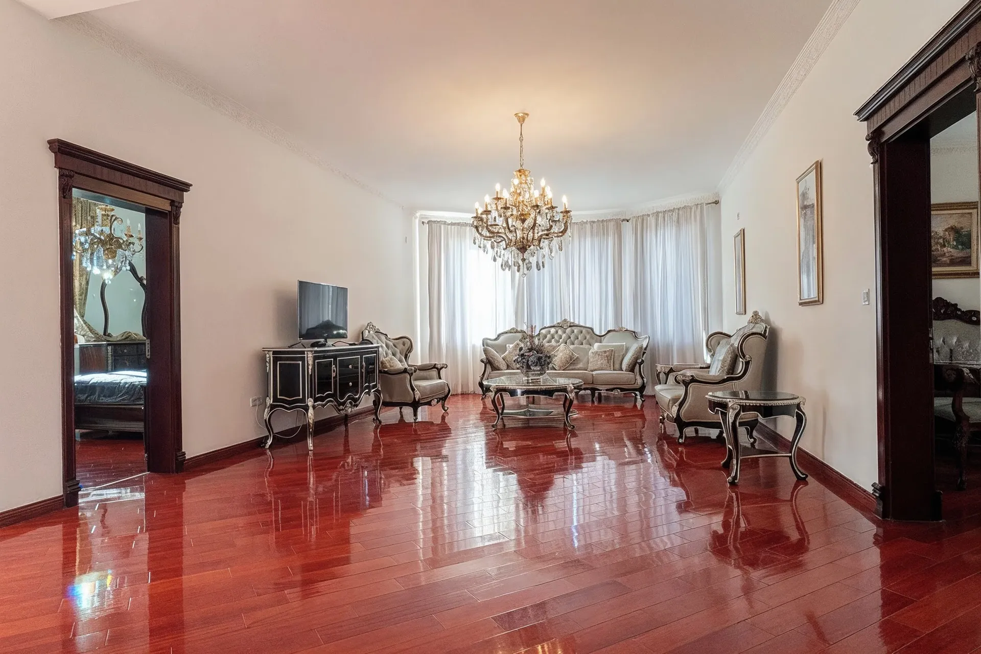 Elegant living room with glossy parquet floor, crystal chandelier, and classic furniture near the window.