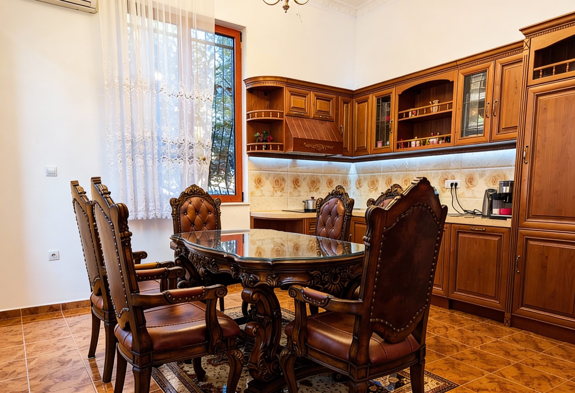 Classic kitchen with carved wooden furniture and a dining area in a villa in Luštica, Montenegro.