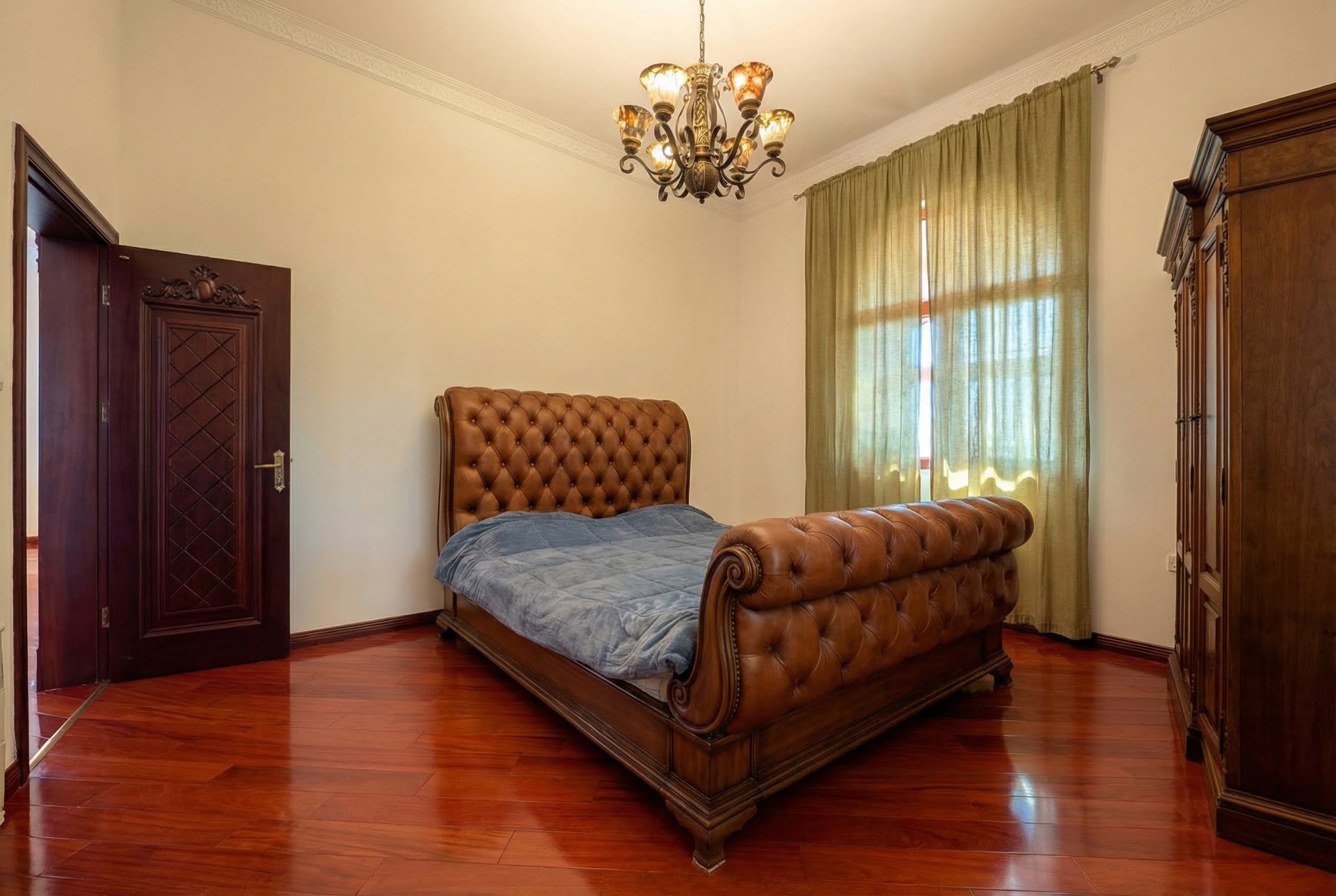 Classic-style bedroom in a villa in Luštica, Montenegro: leather bed, wooden floor, and antique furniture.