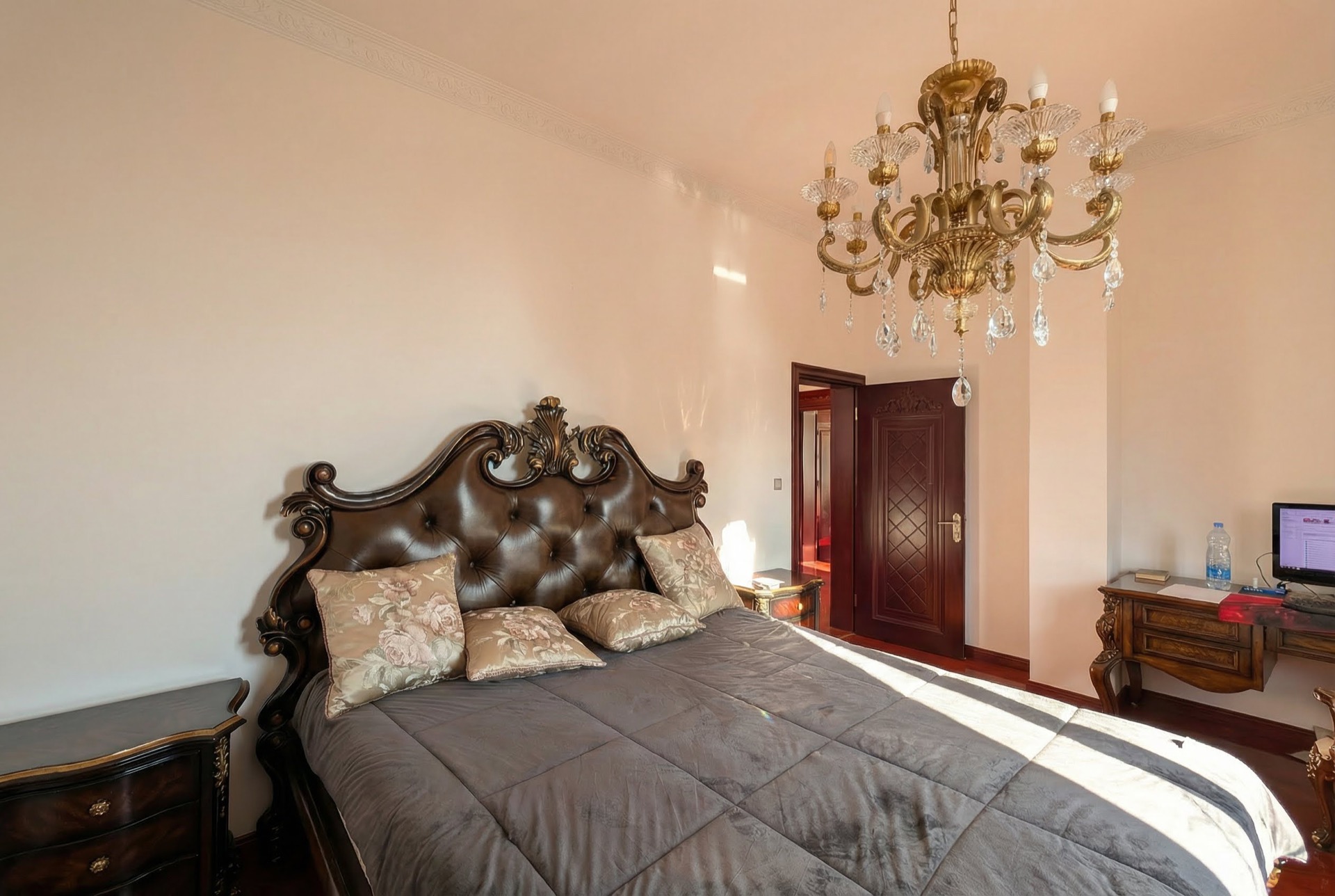 Classic-style bedroom in a villa in Luštica, Montenegro: a solid bed with a leather headboard and a crystal chandelier