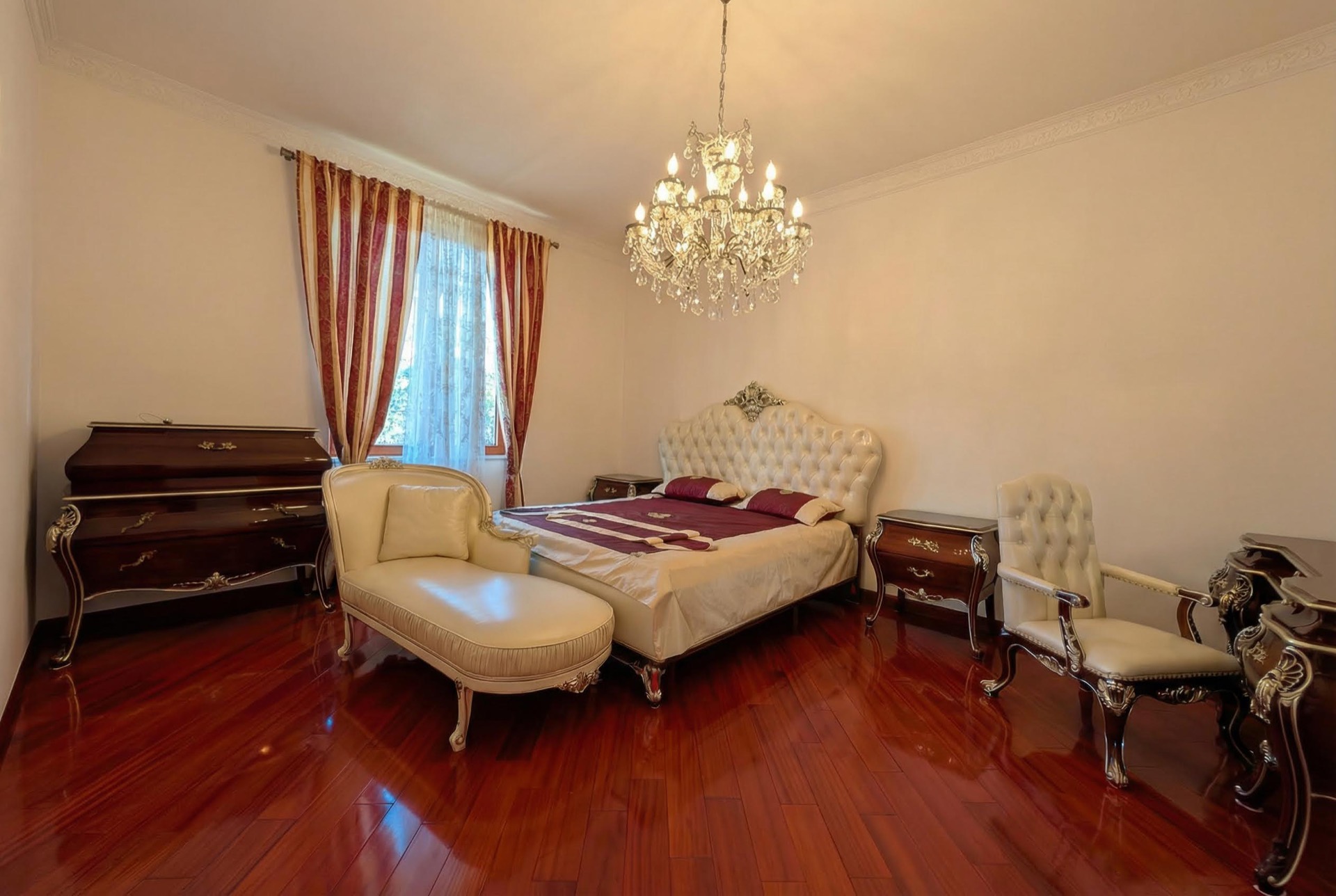 Bedroom in a classic style in a villa in Luštica, Montenegro: double bed, chaise lounge, crystal chandelier, and parquet flooring.
