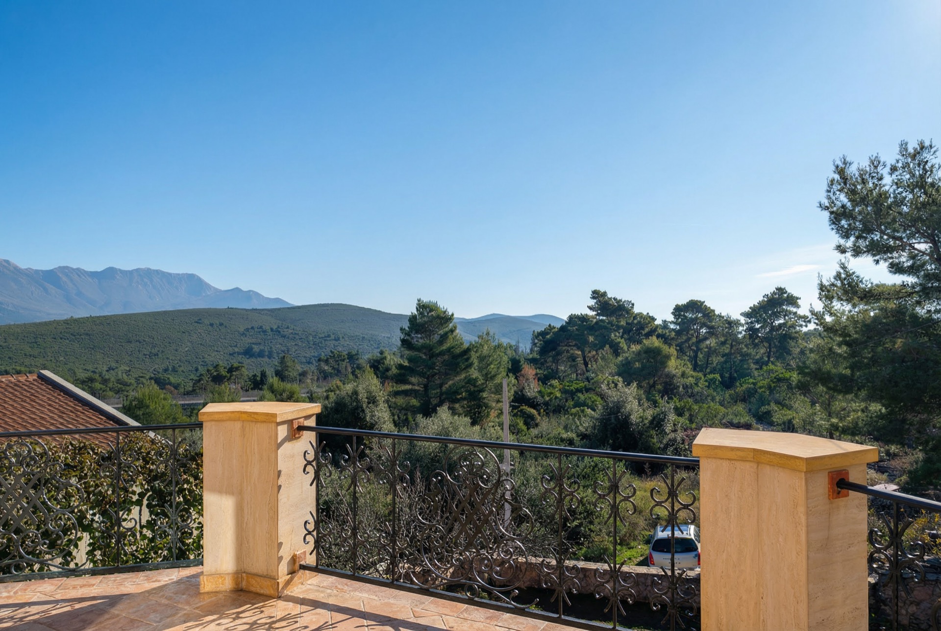 View from the villa terrace in Luštica Bay, Montenegro: wrought-iron railing, panoramic view of the mountains and coniferous forest.