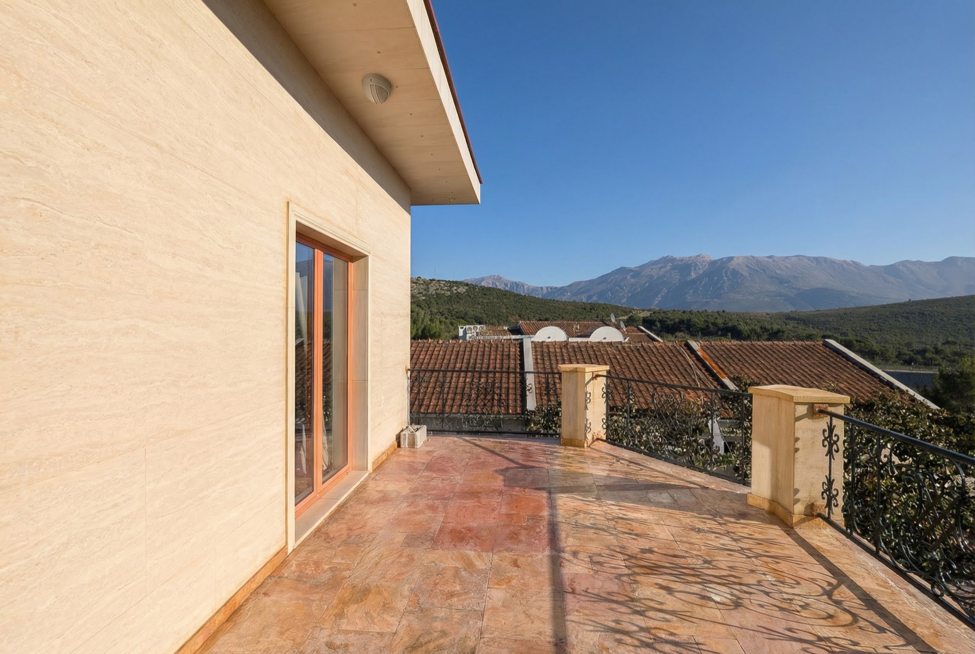 Spacious villa terrace in Luštica Bay, Montenegro, with stone finishes, wrought-iron railing, and mountain views.