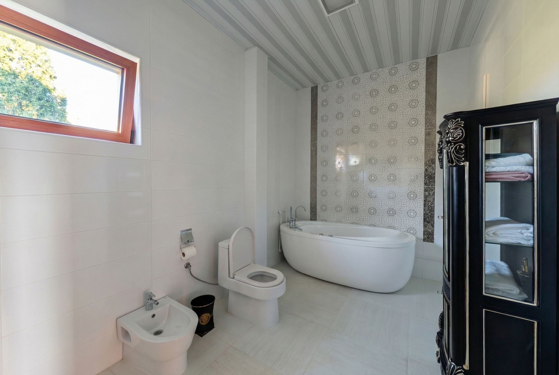 Bathroom in a villa in Luštica, Montenegro: freestanding bathtub, bidet, toilet, and a black display cabinet.