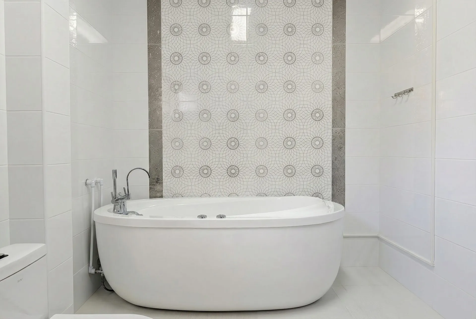 Modern bathroom featuring a white freestanding bathtub and decorative geometric wall tiles.