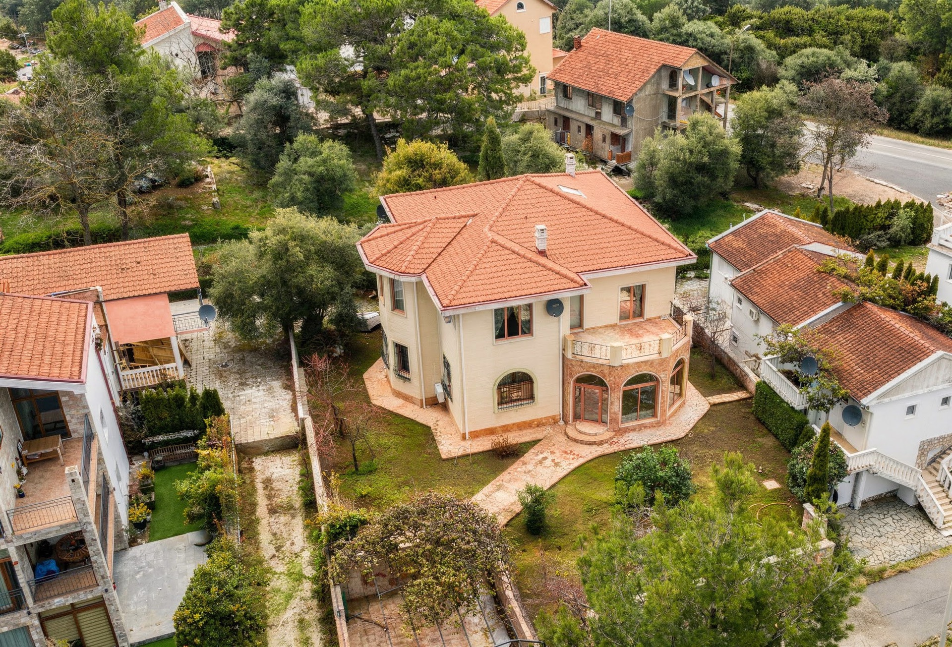 Top view of a two-story villa with a tiled roof and garden in Luštica, Montenegro: house exterior with terrace.