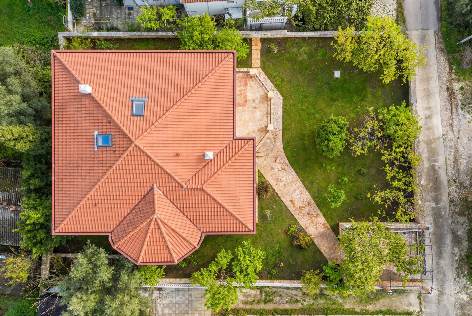 Top view of a villa with a tiled roof, terrace, and green garden in Luštica, Montenegro.