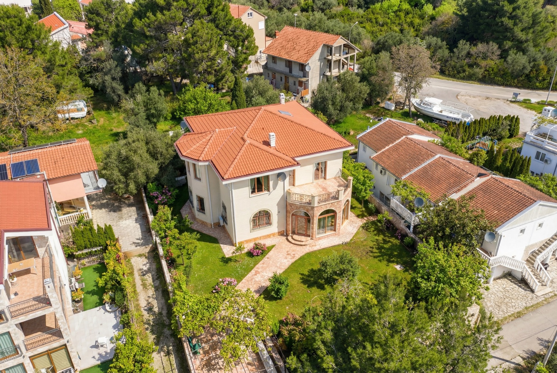Aerial view of a two-story villa with a tiled roof and a green garden in Luštica, Montenegro.