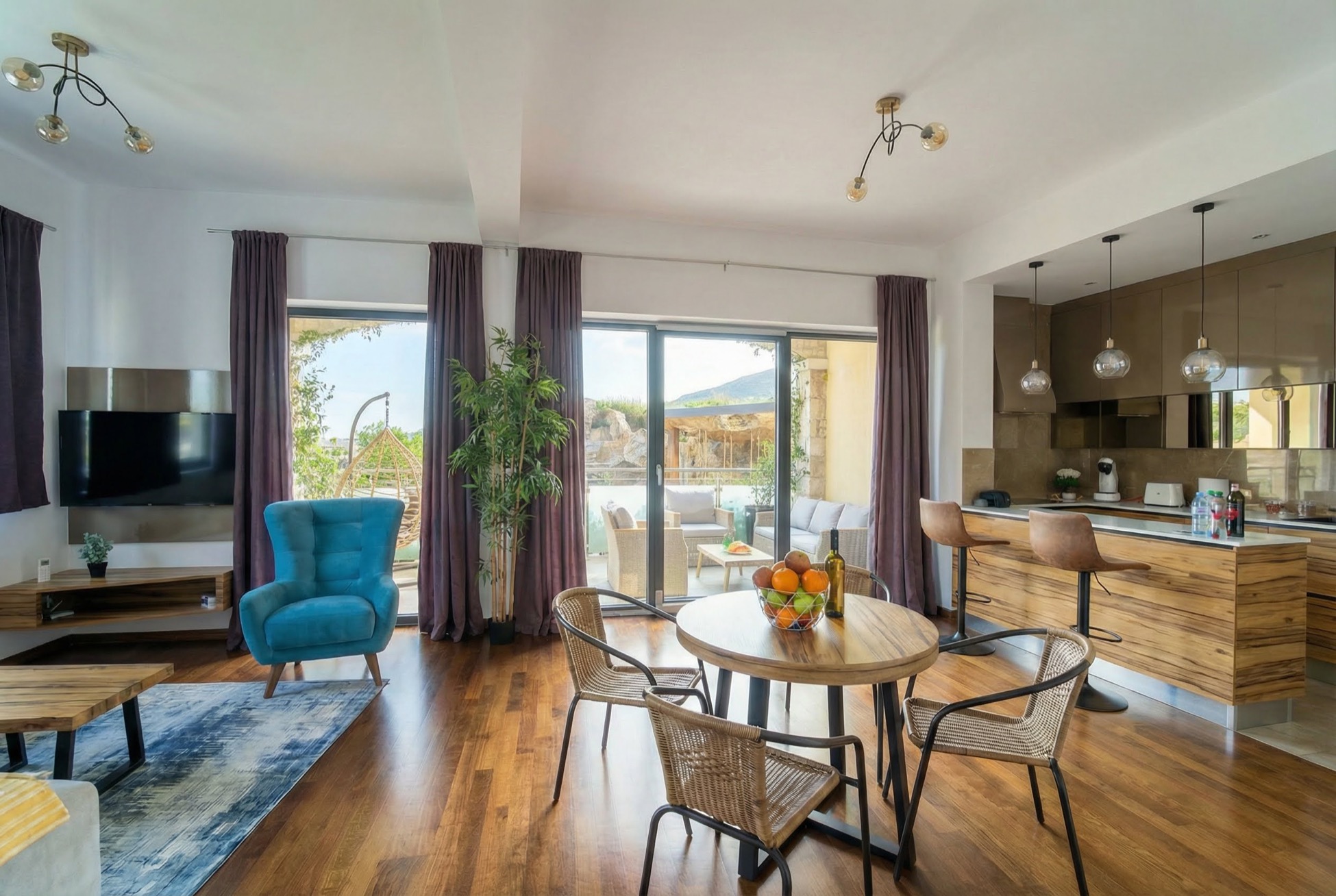 Modern living room with kitchen in an apartment in Bečići, Montenegro: dining area, blue armchair, and access to the terrace.