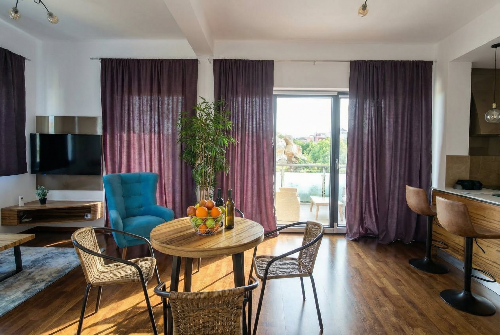 Living room with a dining area in an apartment in Bečići, Montenegro: modern furniture, wicker chairs, and access to the terrace.