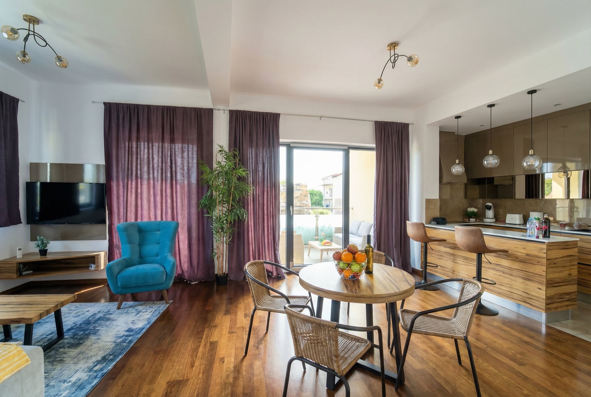 Modern living room with a kitchen in an apartment in Bečići, Montenegro: blue armchair, dining area, and access to the terrace.