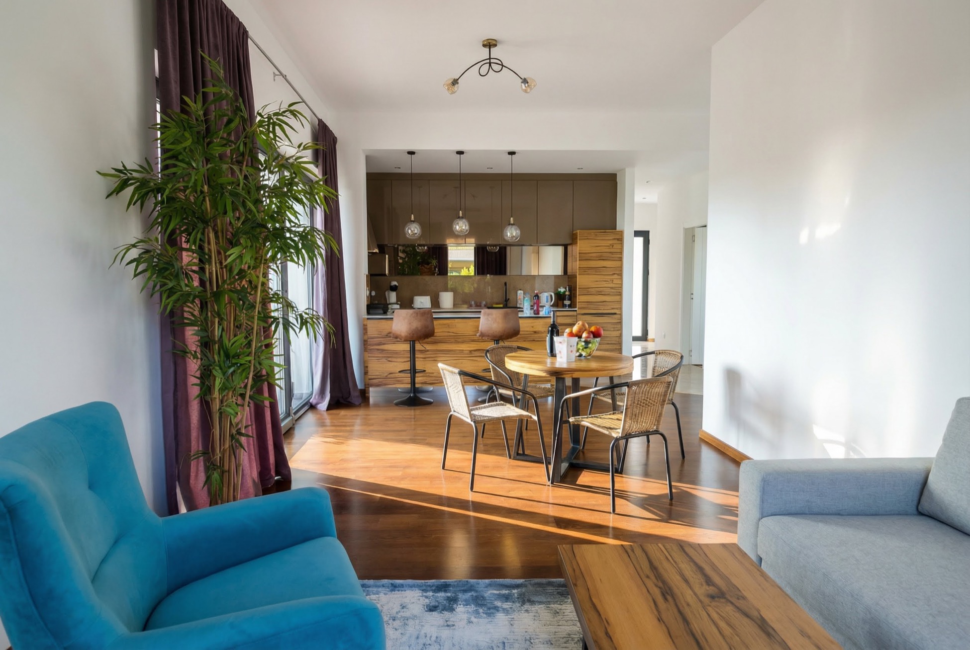 Modern living room with kitchen in an apartment, Becici, Montenegro: blue armchair, dining area, and stylish interior.