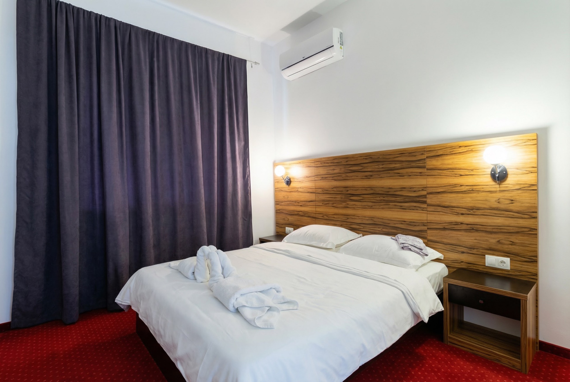 Bedroom in an apartment in Becici, Montenegro: double bed with a wooden headboard, air conditioning, and blackout curtains.