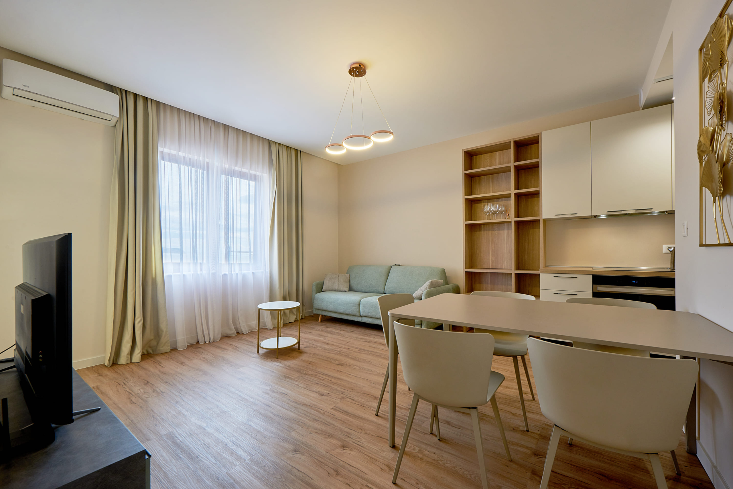 Modern living room with kitchen in an apartment, Bečići, Montenegro: light-colored furniture, sofa, and dining area.