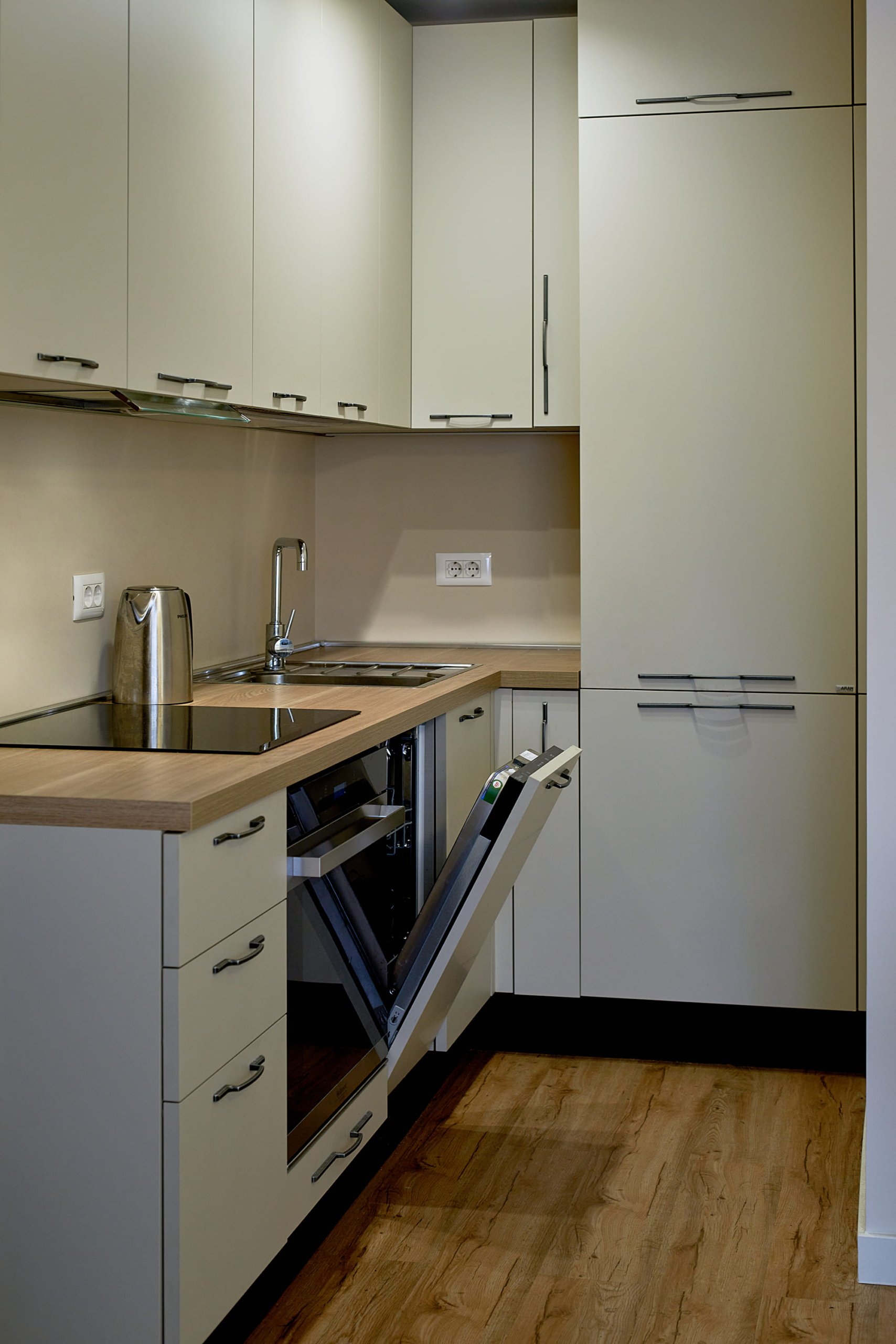 Modern bright kitchen in an apartment in Bečići, Montenegro: built-in appliances, dishwasher, and wooden countertop.