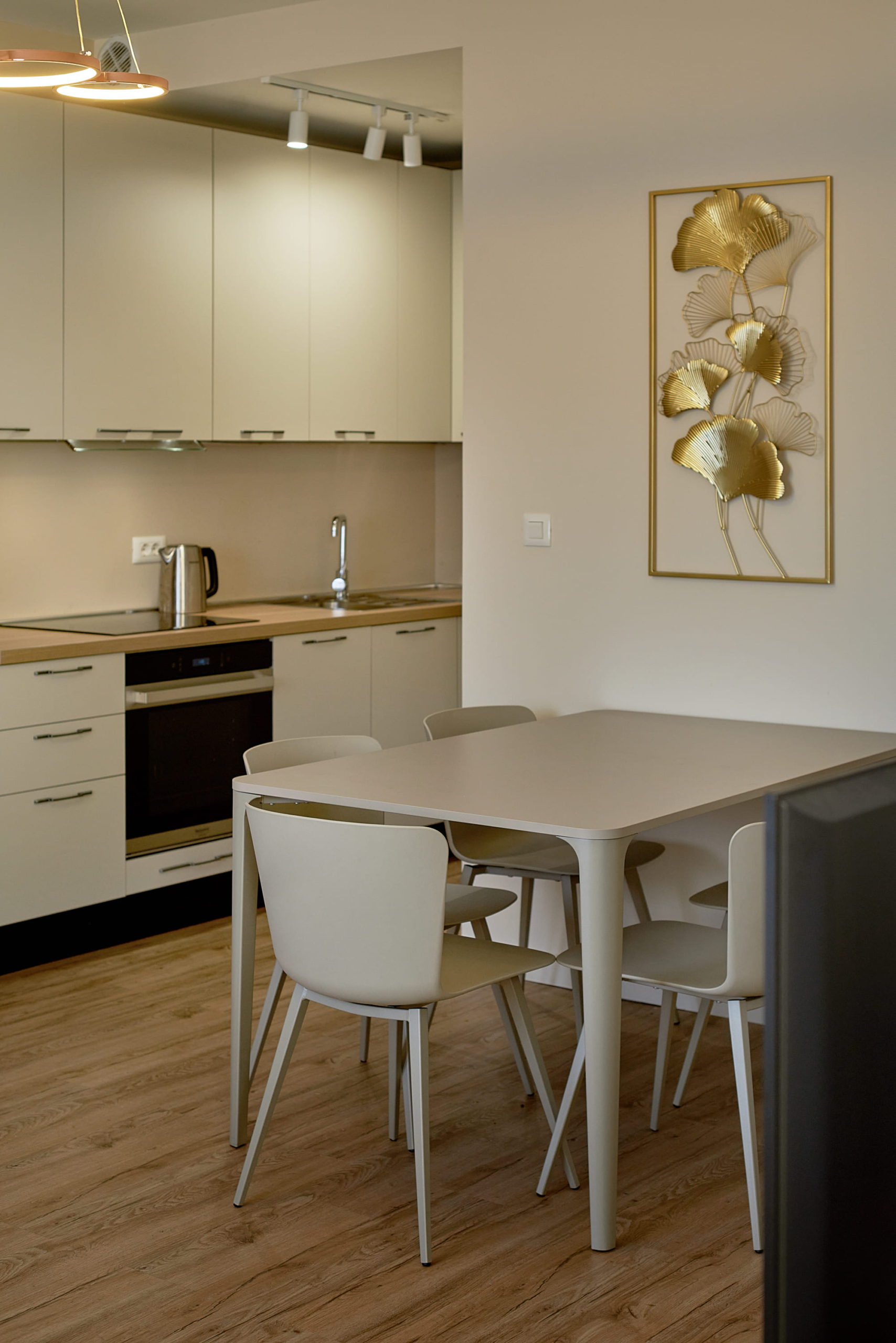 Modern kitchen-dining room in an apartment in Bečići, Montenegro: light-colored kitchen set, dining area, and wall decor.