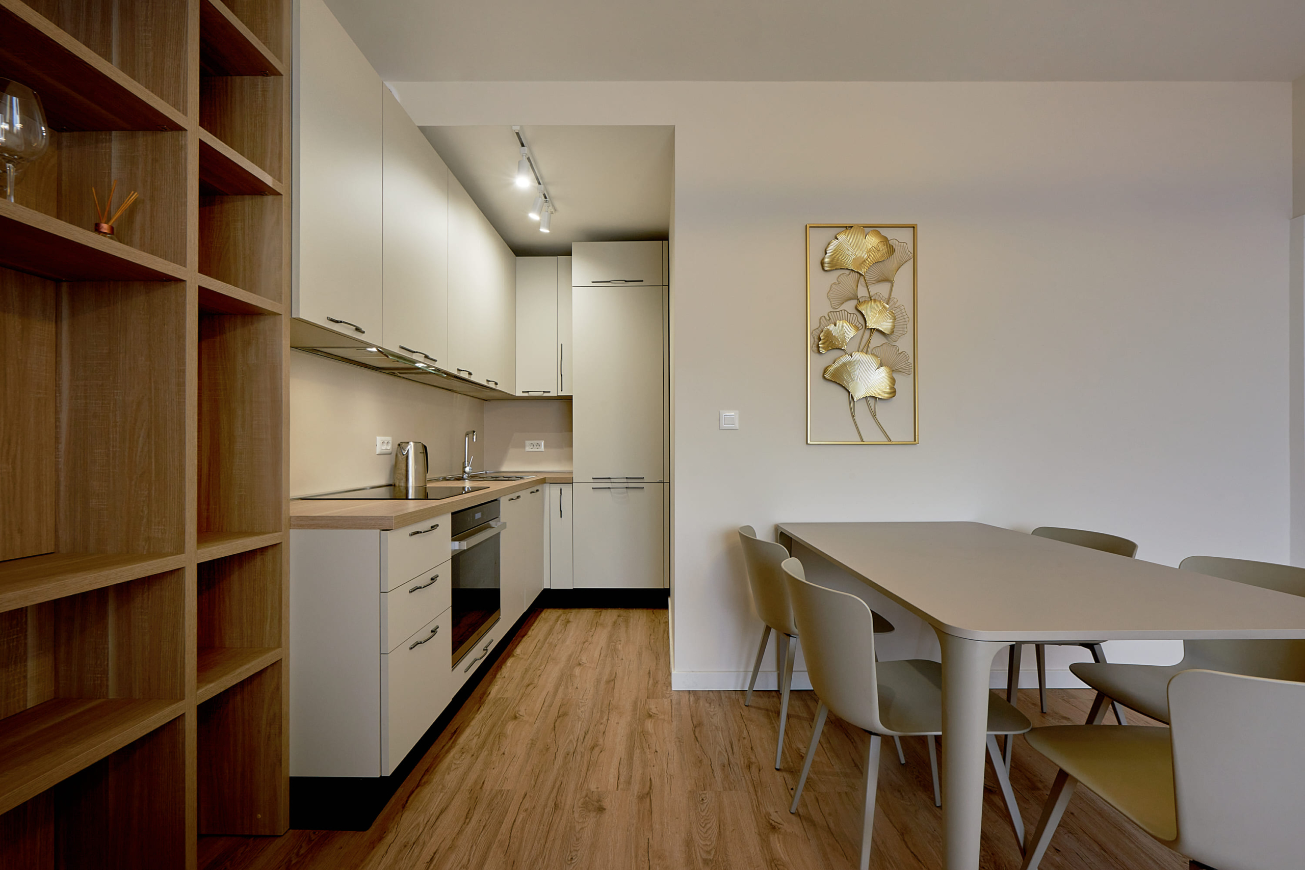 Modern kitchen in an apartment in Bečići, Montenegro: light-colored kitchen set, dining area, and wall decor.