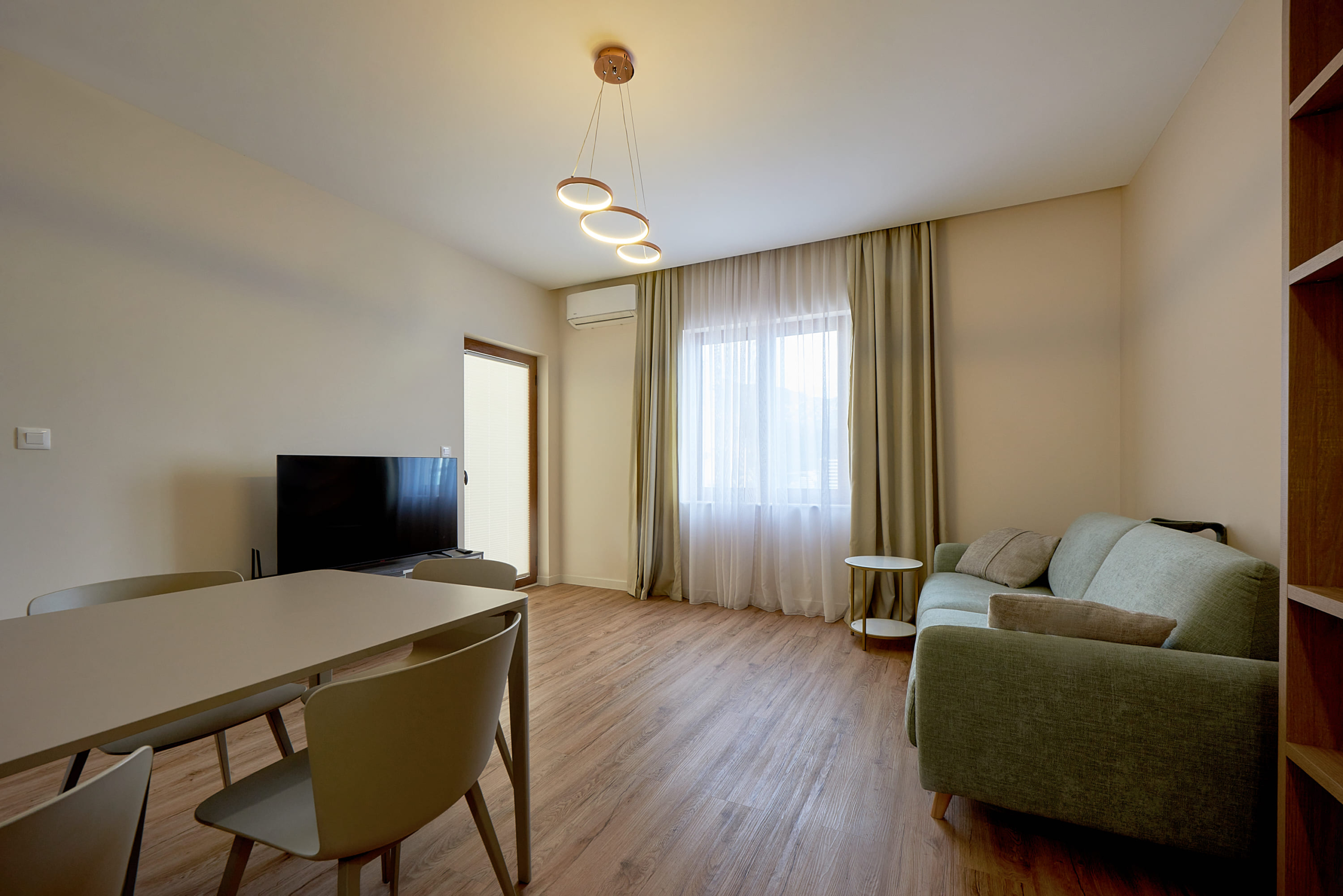 Modern living room with a dining area and sofa in an apartment in Bečići, Montenegro. Bright interior with a TV zone.